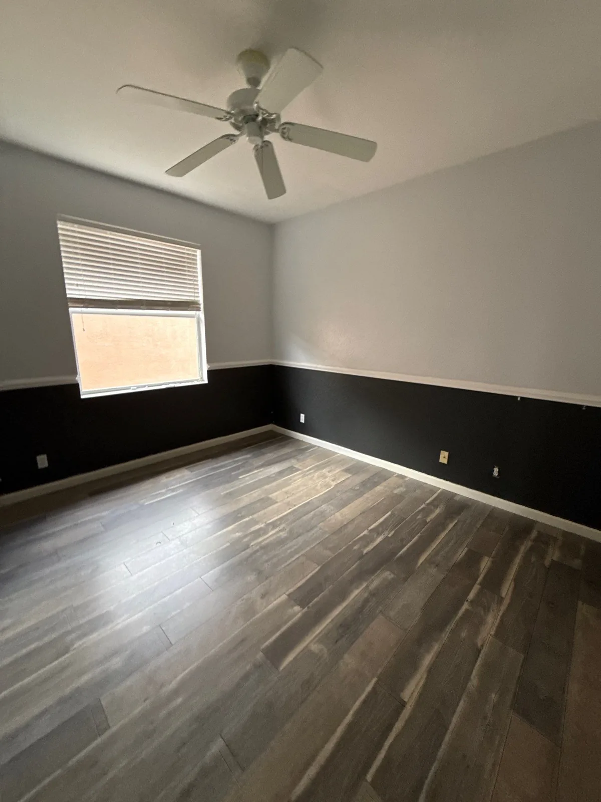 Interior Painting in Coral Gardens, Florida. Empty bedroom painted two-tone with light grey upper walls and dark lower walls divided by a white chair rail.