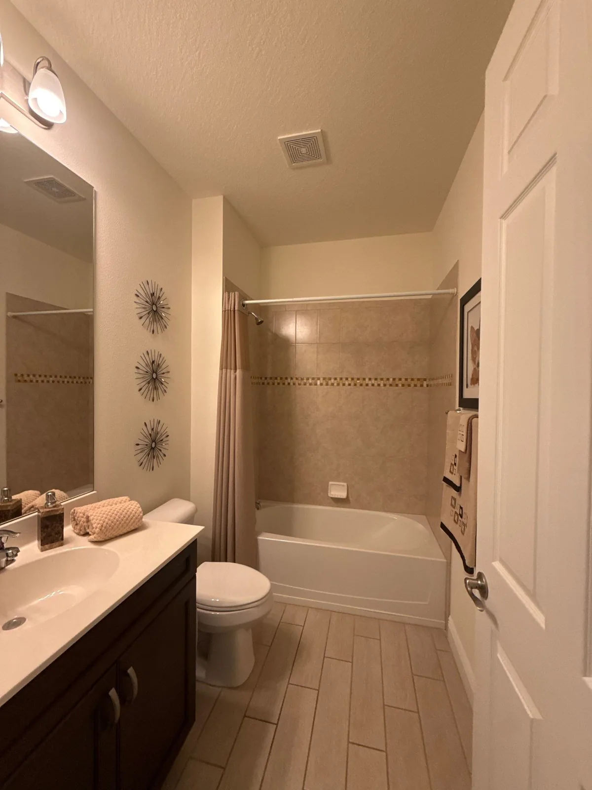 Interior Painting in Florida Ridge, Florida. Finished bathroom with painted walls and ceiling, tiled tub surround, dark vanity with white countertop and framed mirror.
