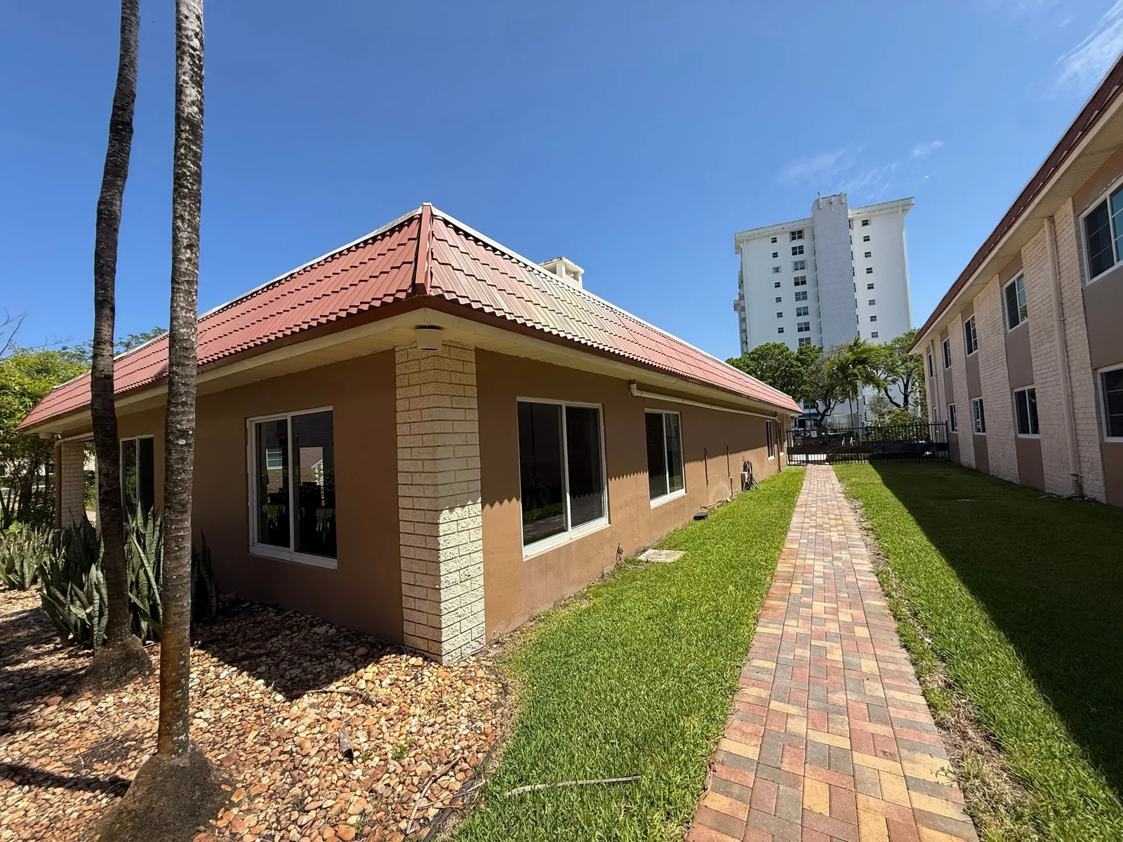 Commercial Painting in Fort Lauderdale, Florida. Corner of a single-storey building with painted stucco and block walls under a tile roof.