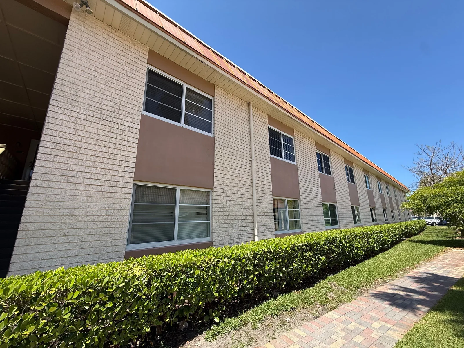 Commercial Painting in Fort Lauderdale, Florida. Long two-storey building elevation with painted block and stucco above a trimmed hedge.