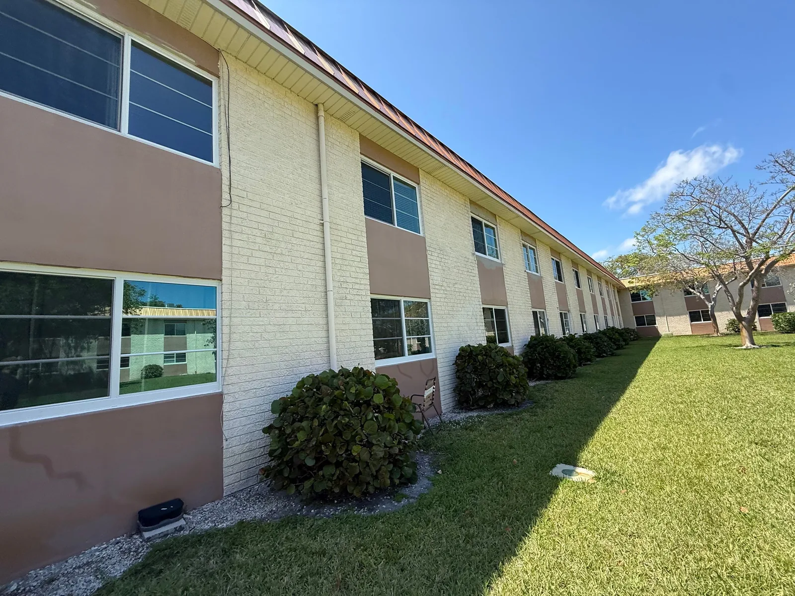 Commercial Painting in Fort Lauderdale, Florida. Two-storey building elevation with painted block and two-tone stucco panels, shrubs along the base.
