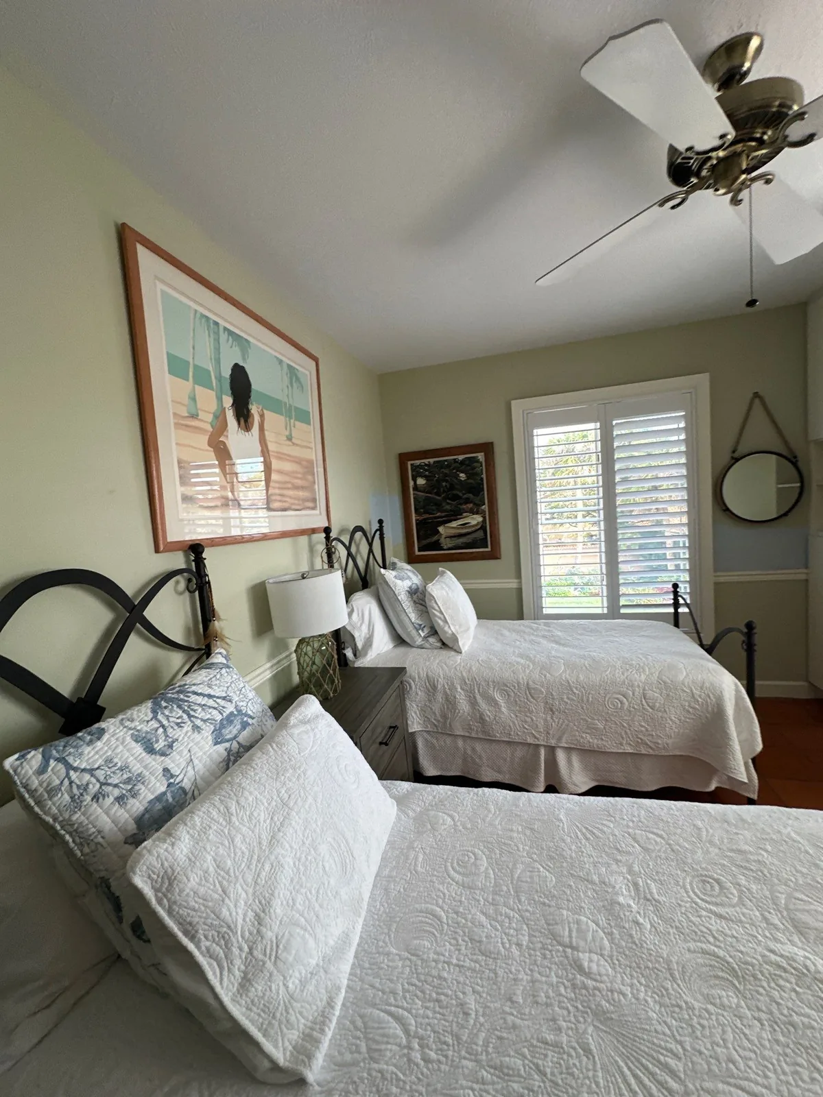 Interior Painting in Jupiter Island, Florida. Furnished guest bedroom with two beds, pale green painted walls, white trim and plantation shutters.