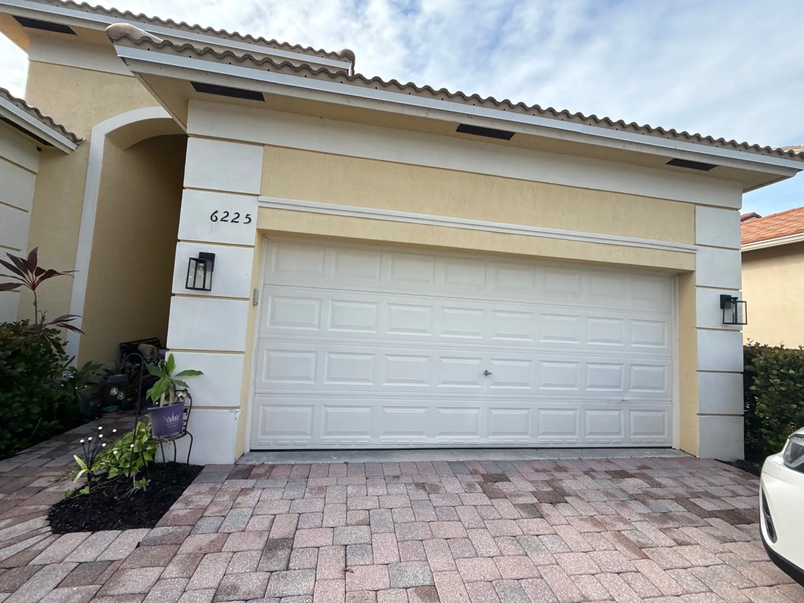 Exterior Painting in Lakewood Park, Florida. Single-storey stucco home exterior with white two-car garage door, tile roof and paver driveway.