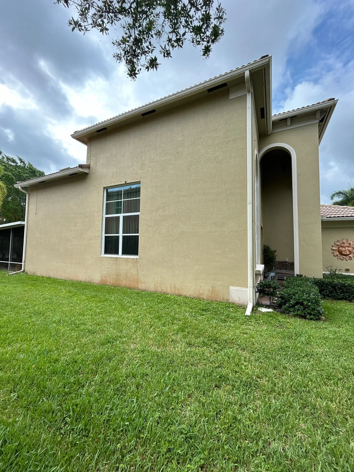 Exterior Painting in Lakewood Park, Florida. Side elevation of a single-storey stucco home in tan with white window trim and tile roof.