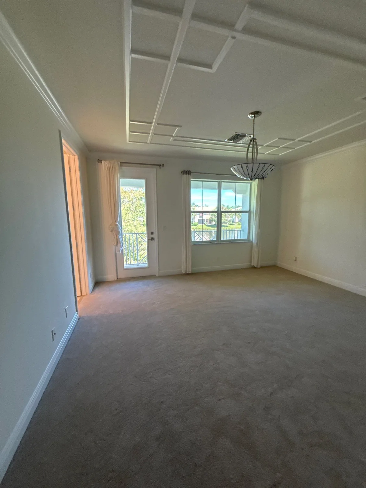 Interior Painting in North Palm Beach, Florida. Empty living room with painted walls, crown molding, coffered ceiling detail and French doors.