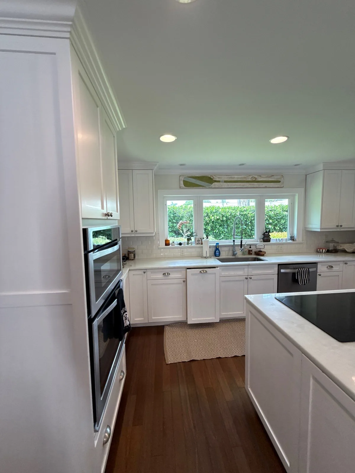 Cabinet Refinishing in North River Shores, Florida. Kitchen with white shaker cabinets, white countertops, built-in wall ovens and a window over the sink.