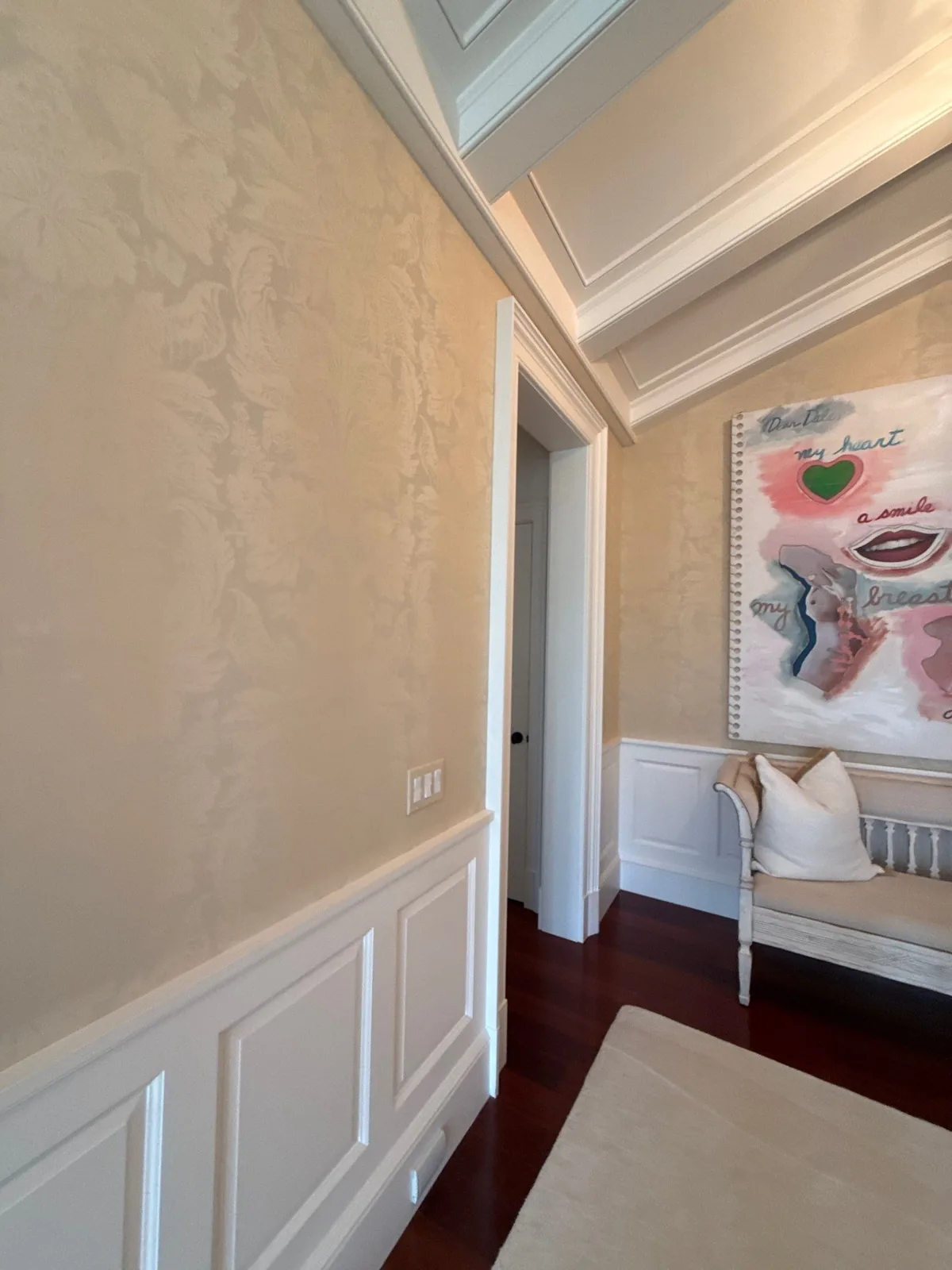 Interior Painting in Palm Beach, Florida. Hallway with cream textured plaster walls, white raised-panel wainscoting and white beamed ceiling.