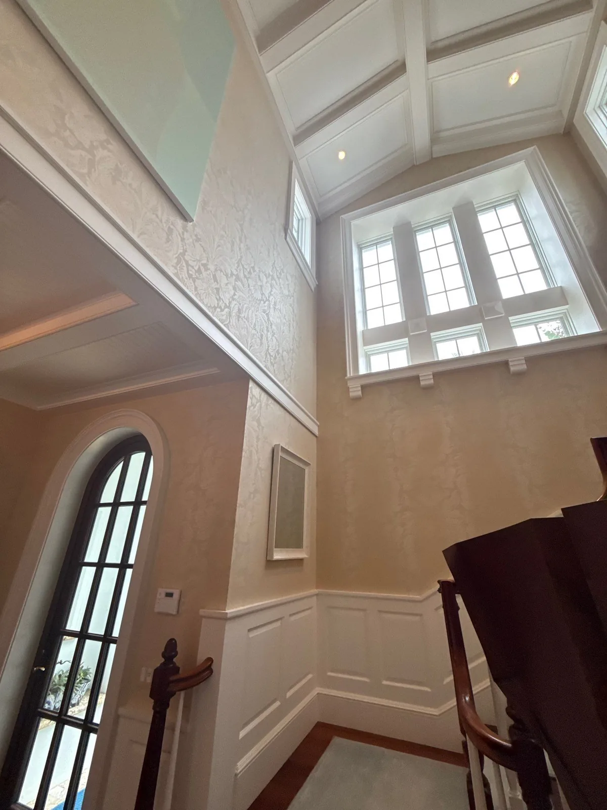 Interior Painting in Palm Beach, Florida. Two-storey entry with white vaulted beamed ceiling, cream textured walls, white wainscoting and an arched glazed door.