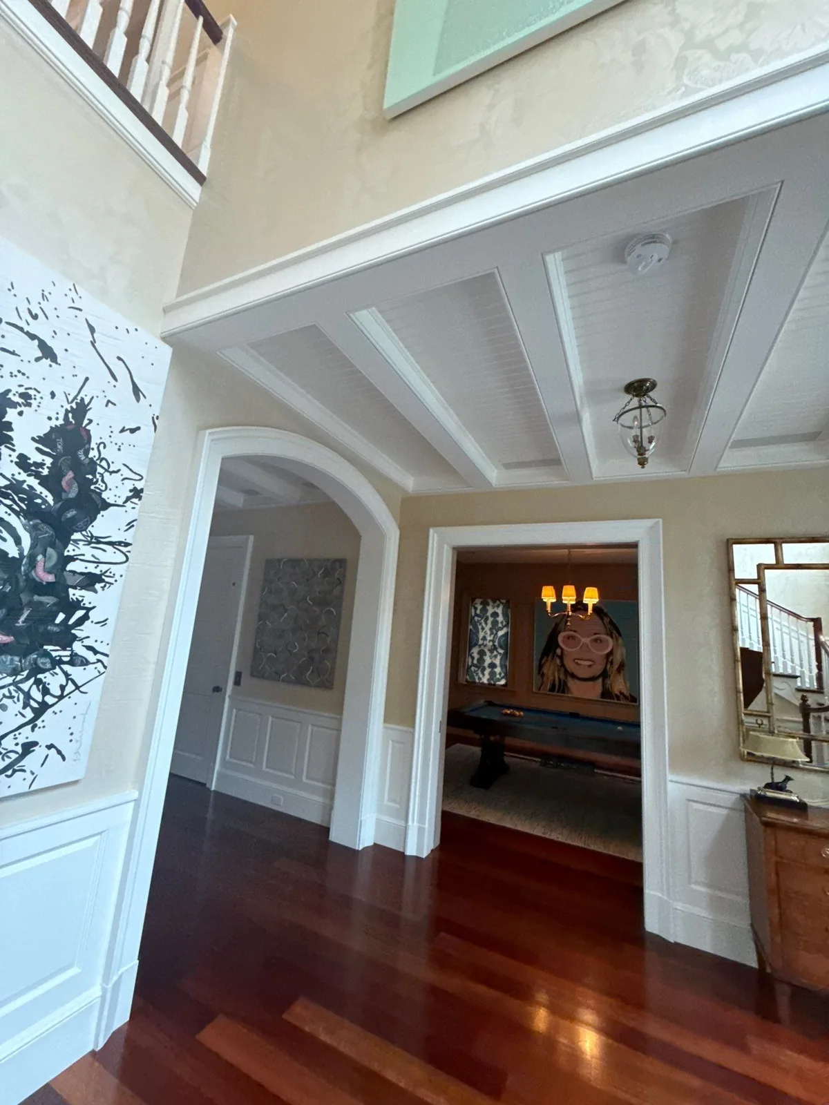 Interior Painting in Palm Beach, Florida. Two-storey foyer with white beamed ceiling, arched cased opening, white wainscoting and dark hardwood floor.