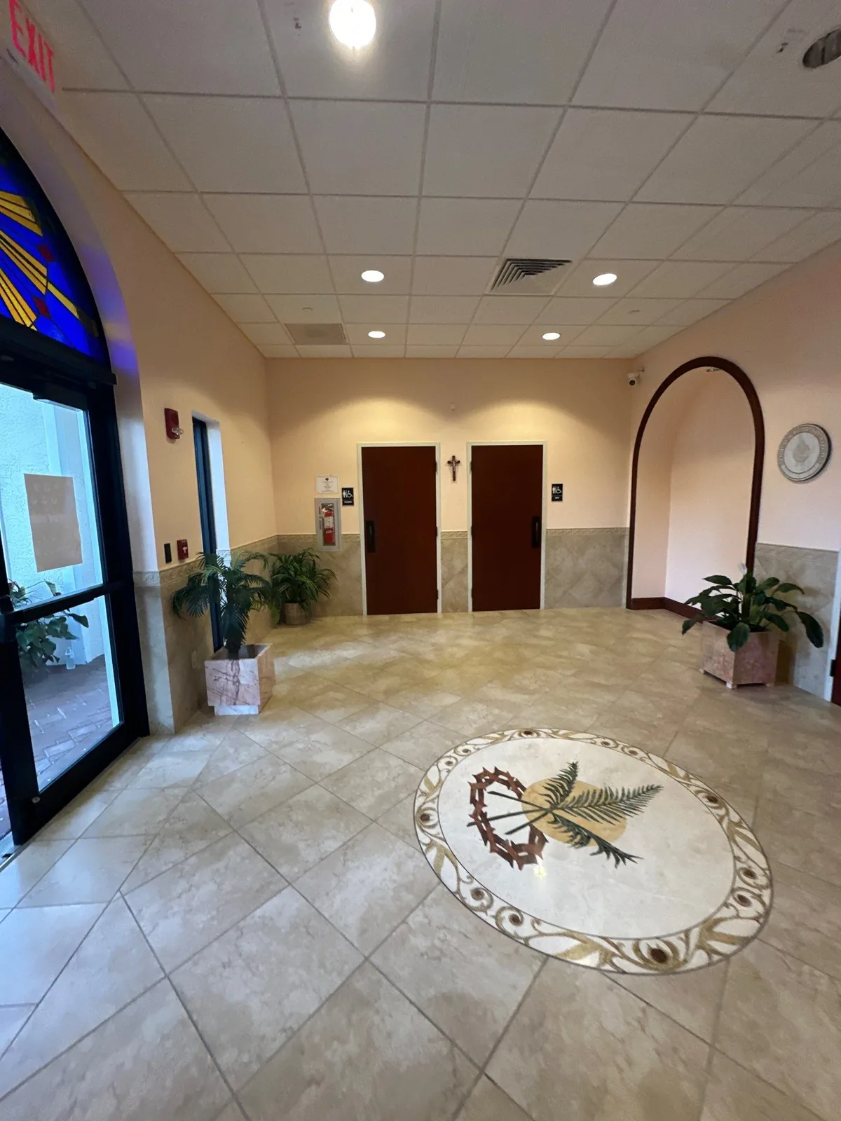 Commercial Painting in Palm City, Florida. Commercial building lobby with painted beige walls, tiled wainscot band, arched openings, potted plants and a tile floor medallion.