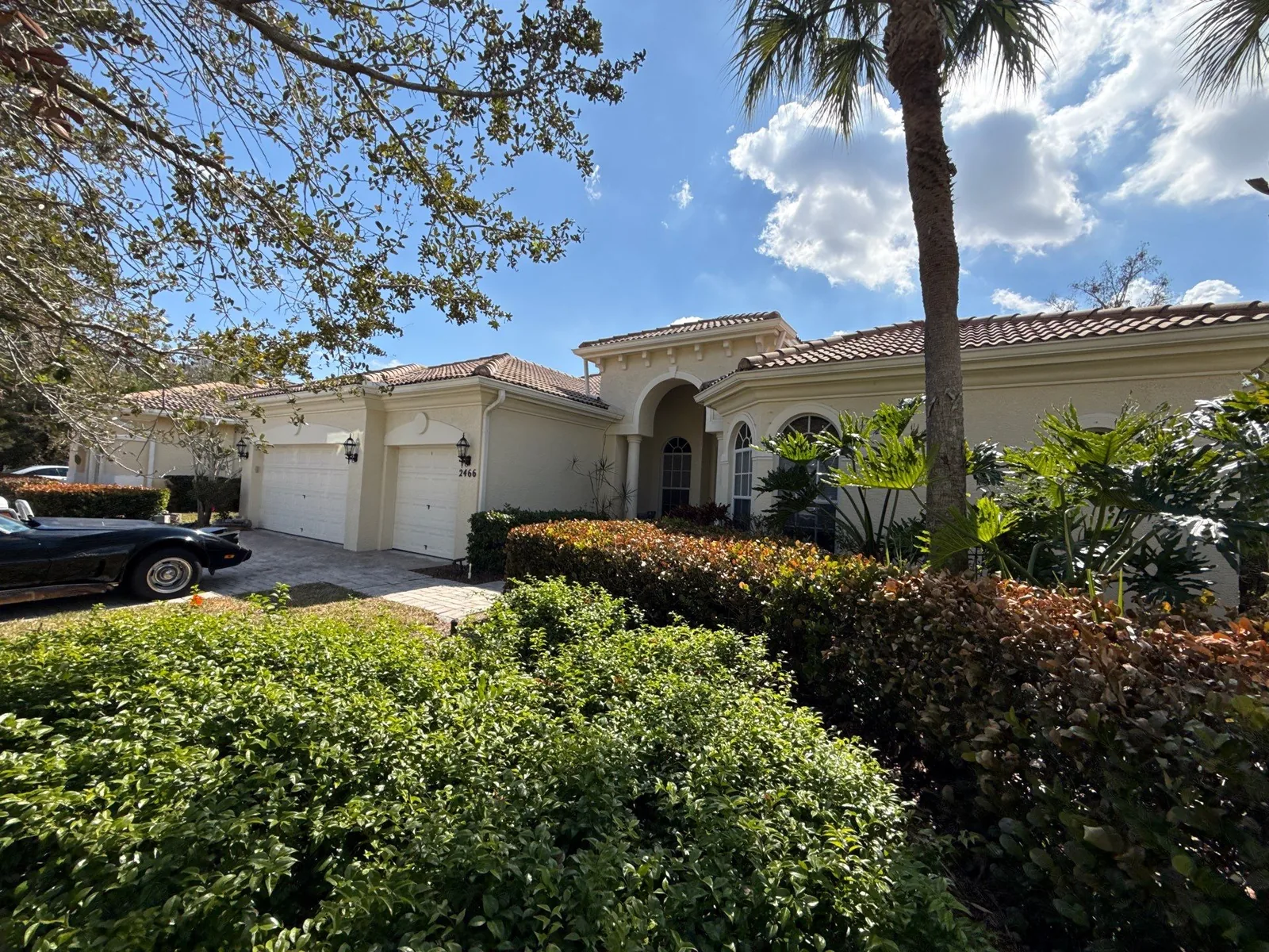 Exterior Painting in Palm City, Florida. Single-storey home front elevation in cream stucco with a barrel tile roof, arched entry and three-car garage.