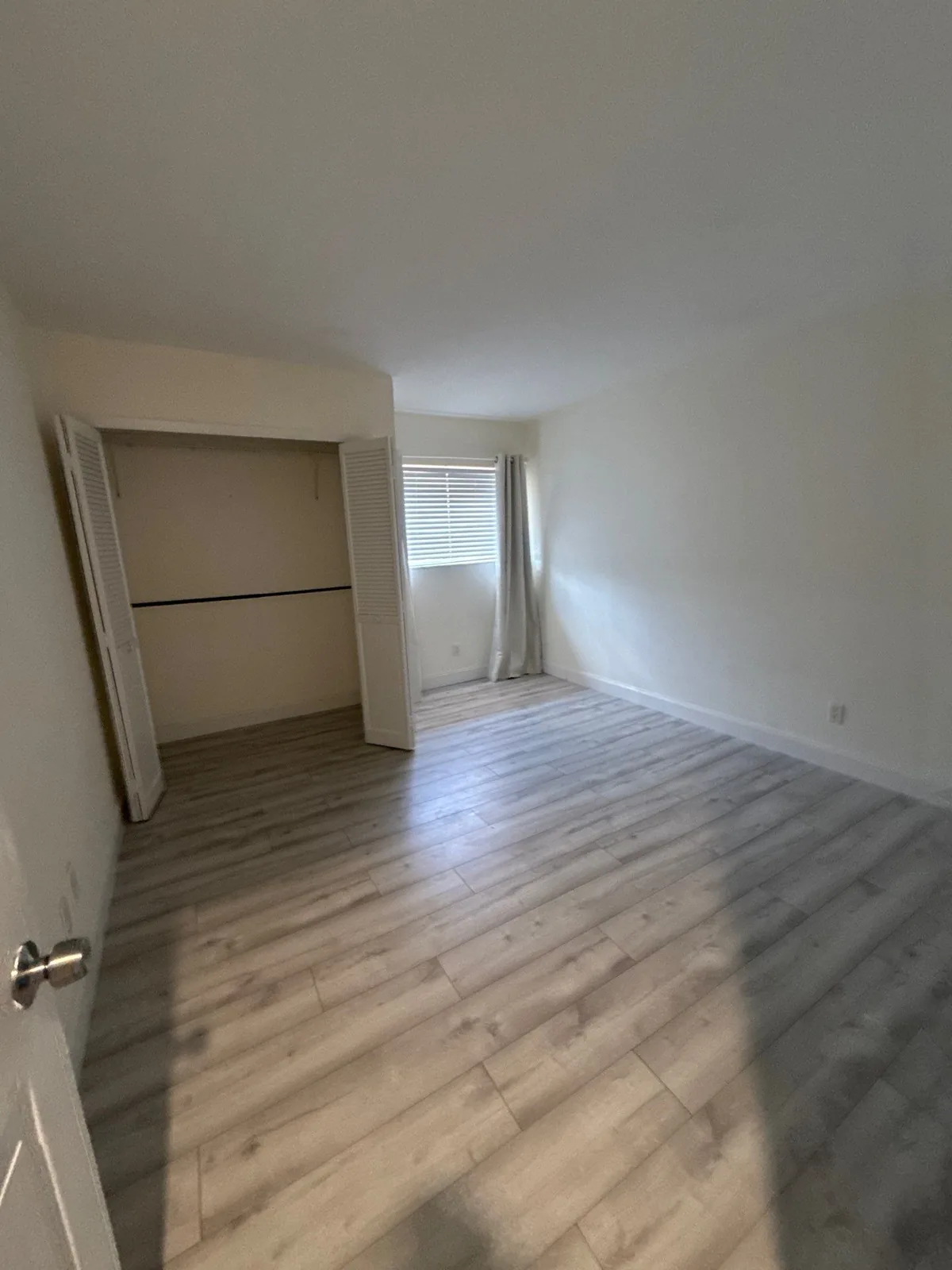 Interior Painting in Palm City, Florida. Empty bedroom with white painted walls, an open closet and wood-look plank flooring.