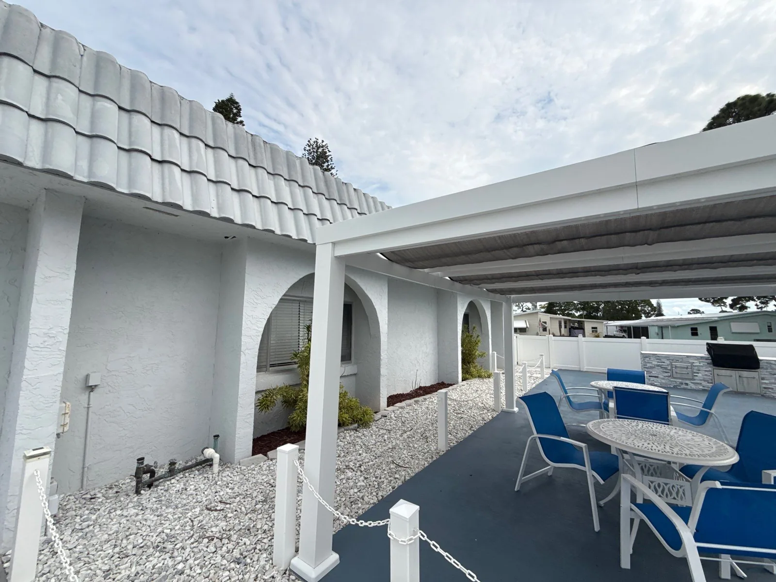 Commercial Painting in Paradise Park, Florida. White painted stucco arches and columns on a tile-roofed building, with a covered patio and blue chairs alongside.