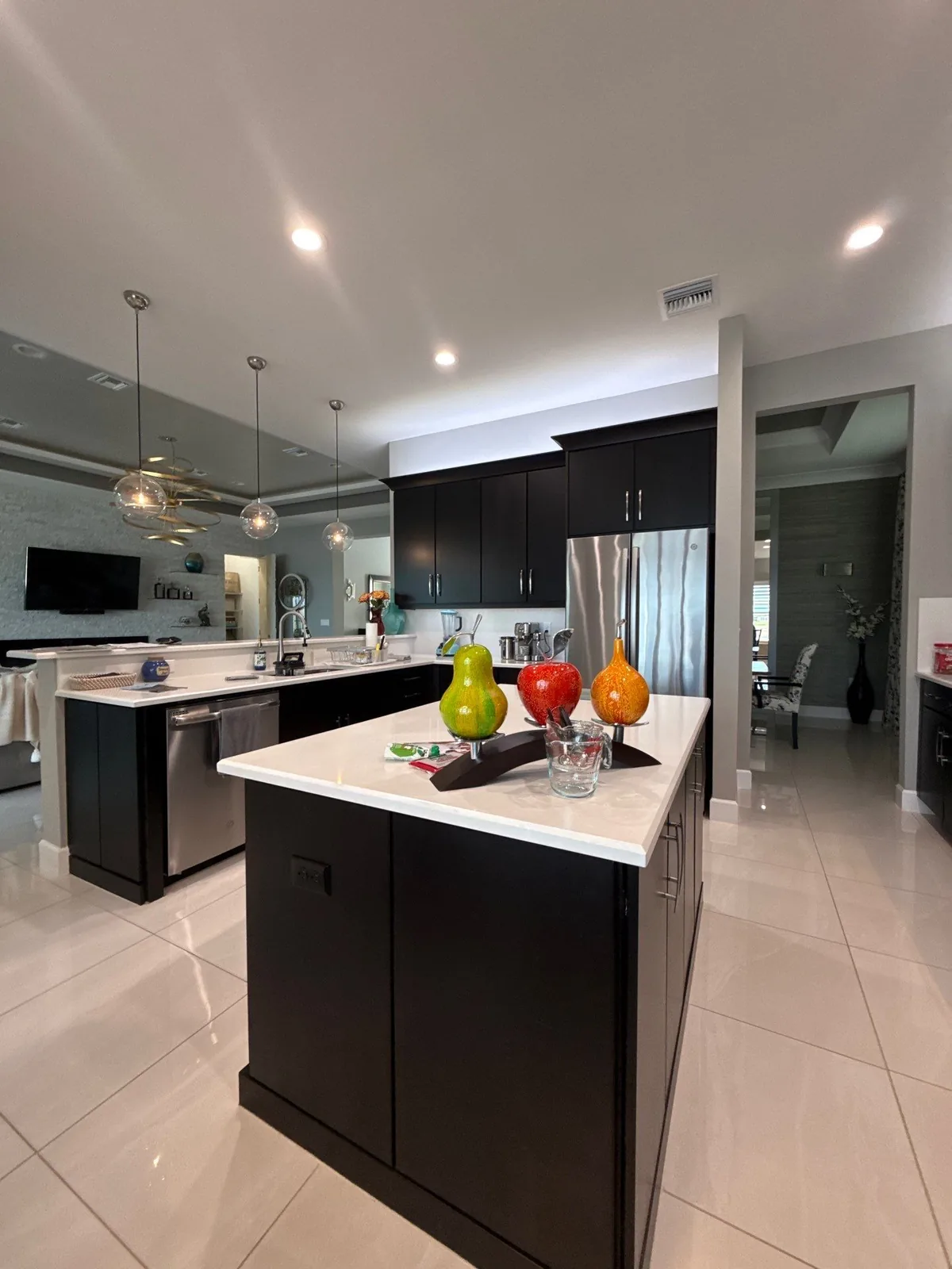 Cabinet Refinishing in Port Saint Lucie, Florida. Kitchen with dark espresso-finish cabinets, white quartz island and countertops, pendant lights and stainless appliances.