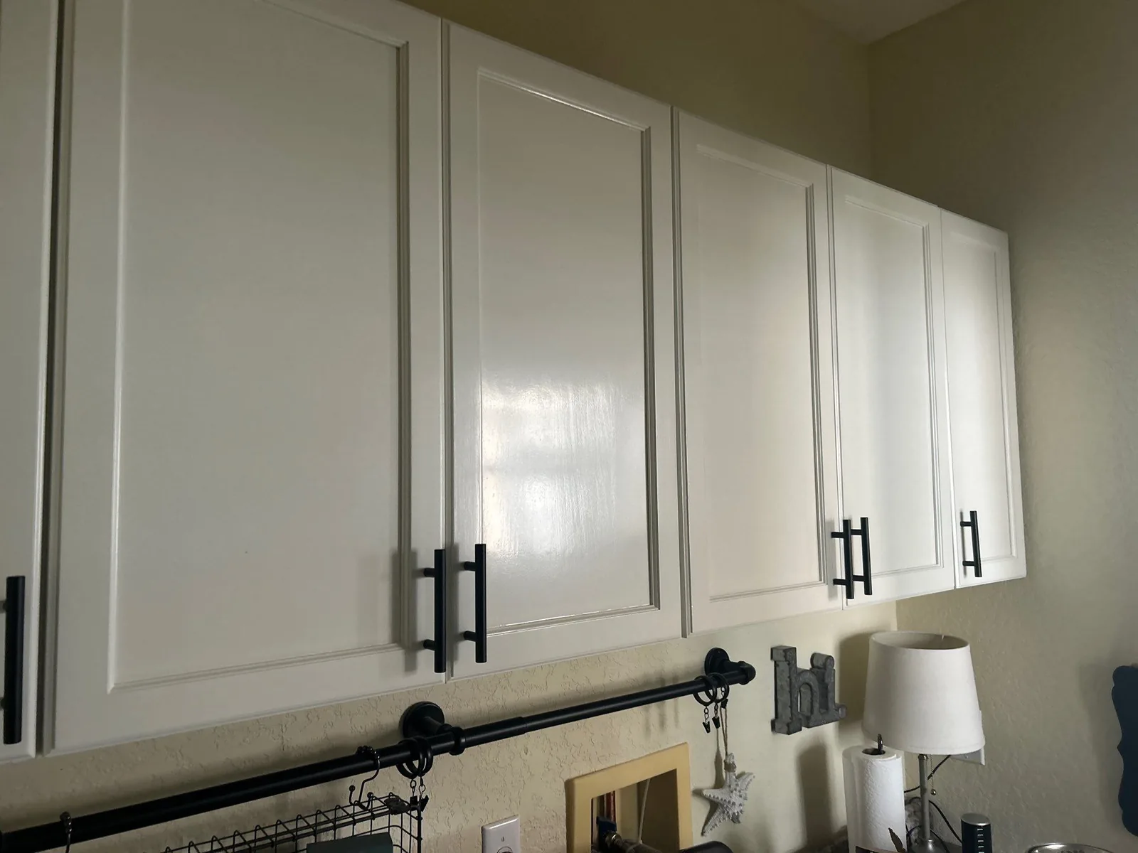 Cabinet Refinishing in Port Saint Lucie, Florida. Run of white-painted upper kitchen cabinets with black bar pulls.