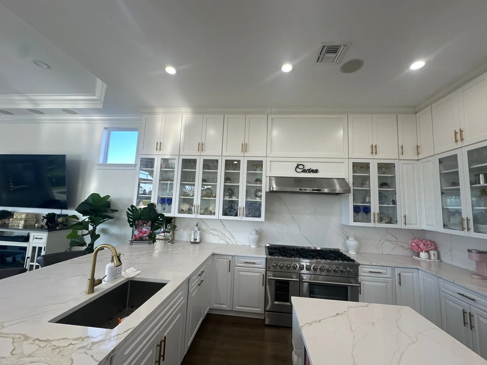 Cabinet Refinishing in Port Saint Lucie, Florida. White kitchen cabinets with glass-front uppers and gold hardware, quartz counters and stainless range.