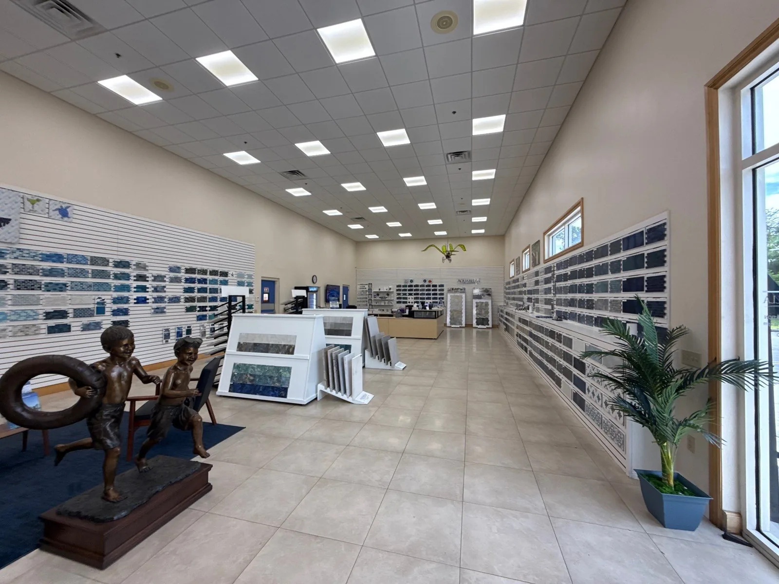 Commercial Painting in Port Saint Lucie, Florida. Commercial showroom interior with beige painted walls, a white suspended ceiling grid, tile floor and wall-mounted sample display racks.