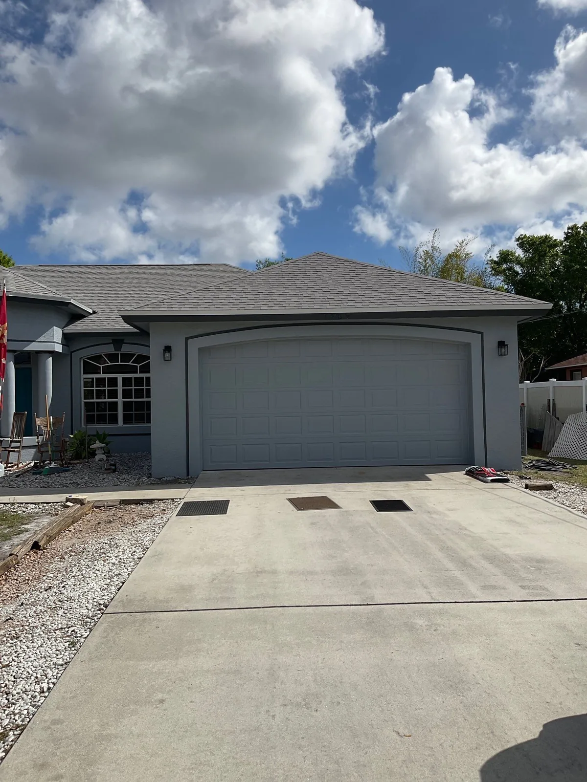 Exterior Painting in Port Saint Lucie, Florida. Front elevation of a single-storey home painted grey with a matching grey garage door and concrete driveway.