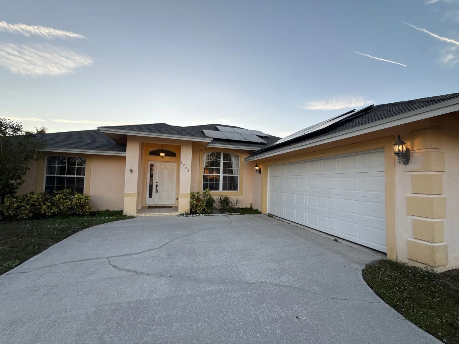 Exterior Painting in Port Saint Lucie, Florida. Single-storey stucco house painted cream with white garage door and trim, concrete driveway.