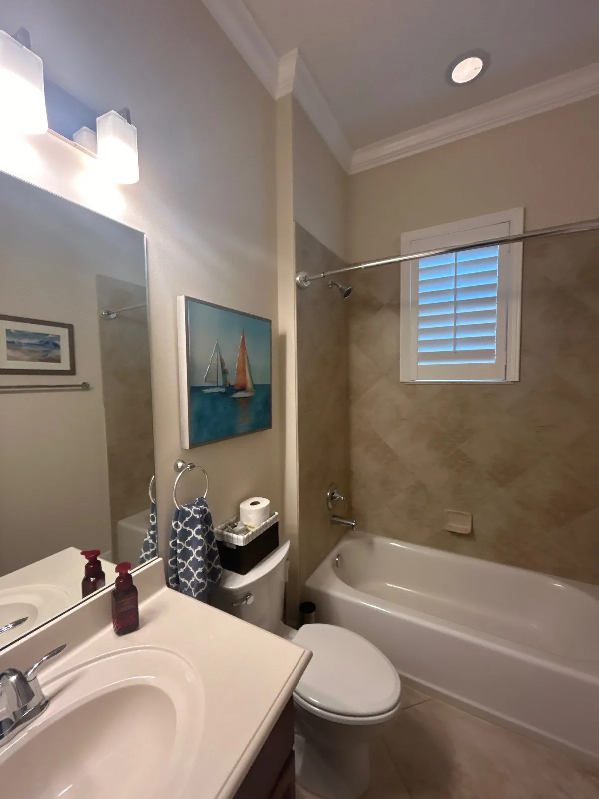 Interior Painting in Port Saint Lucie, Florida. Finished bathroom with painted walls, white crown moulding, vanity mirror and bathtub surround.