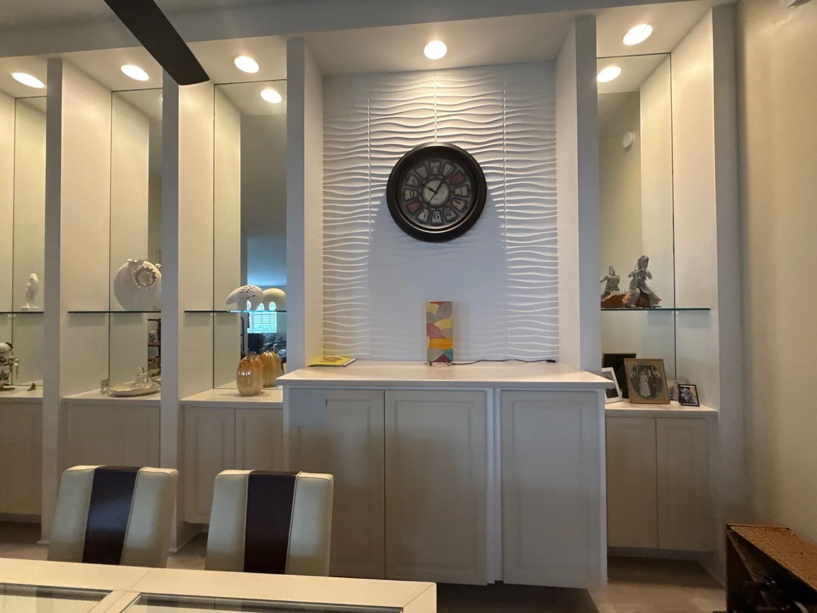 Interior Painting in Port Saint Lucie, Florida. Dining room with white built-in cabinetry, mirrored surrounds and a textured white accent wall under recessed ceiling lights.