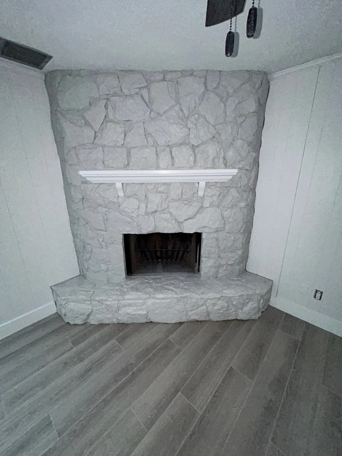 Interior Painting in Port Saint Lucie, Florida. Corner stone fireplace painted white with a white mantel shelf, flanked by white painted wall panelling.