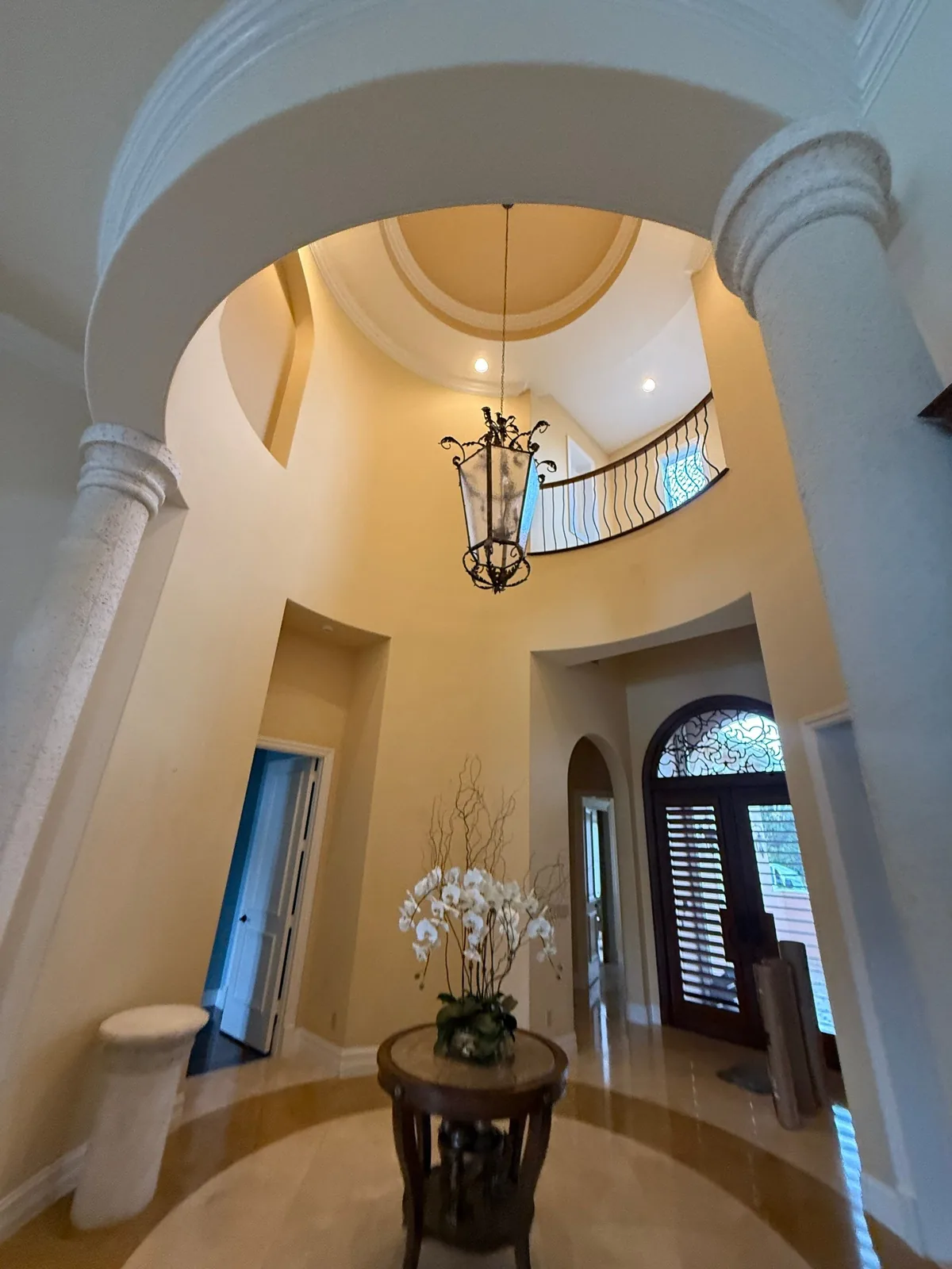 Interior Painting in Port Saint Lucie, Florida. Two-storey entry rotunda with domed painted ceiling, columns, lantern chandelier and curved balcony railing.
