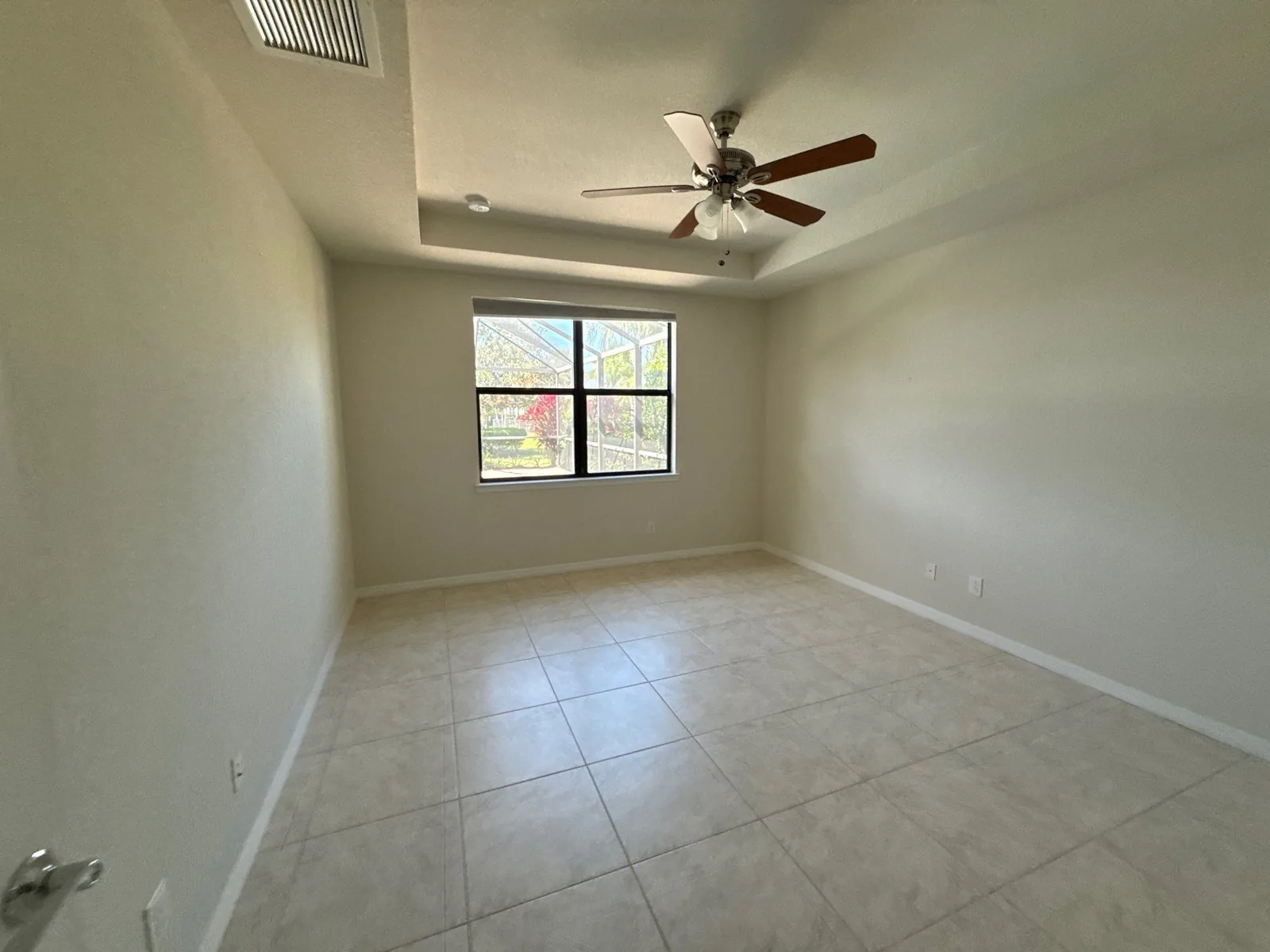 Interior Painting in Port Saint Lucie, Florida. Empty bedroom with neutral painted walls, tray ceiling, ceiling fan and tile floor.