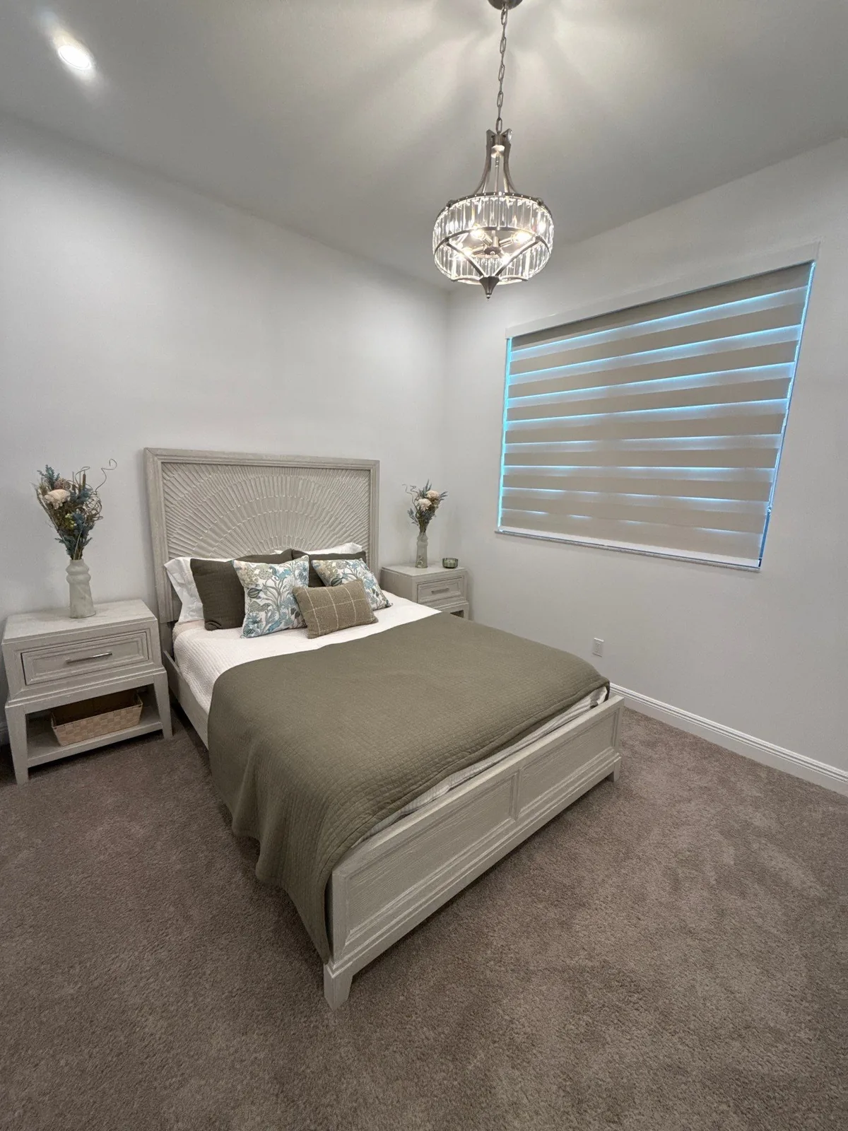 Interior Painting in Port Saint Lucie, Florida. Finished bedroom with white walls and ceiling, upholstered bed with pillows, nightstands and a pendant light.