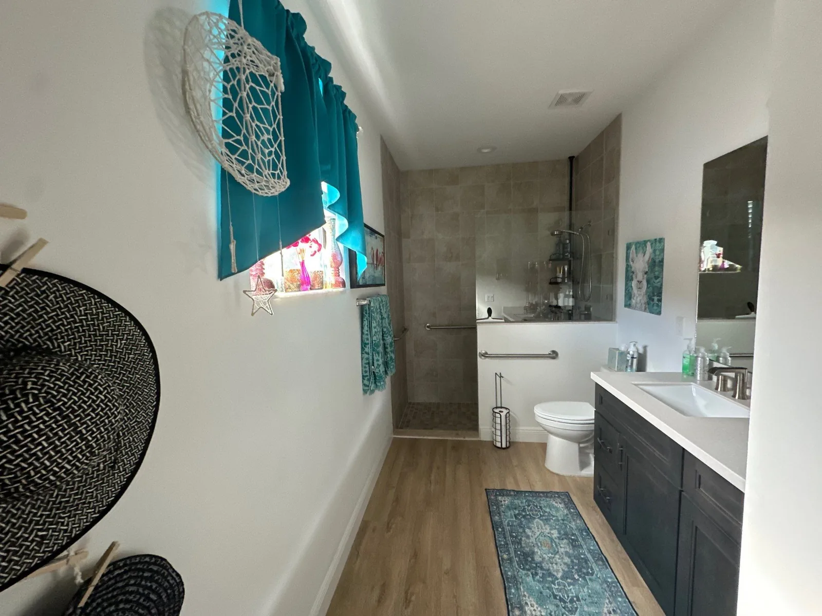 Interior Painting in Port Saint Lucie, Florida. Bathroom with white painted walls and ceiling, tiled walk-in shower, dark vanity, wood-look flooring.