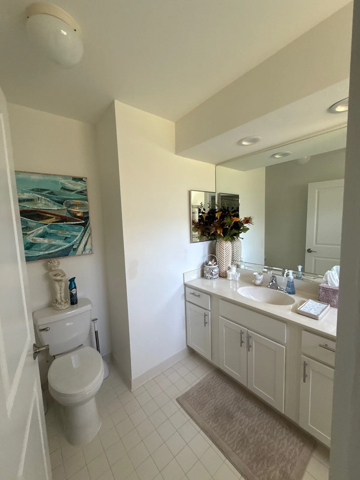 Interior Painting in Royal Palm Beach, Florida. Finished bathroom with painted white walls and ceiling, white vanity cabinets, large mirror and tile floor.