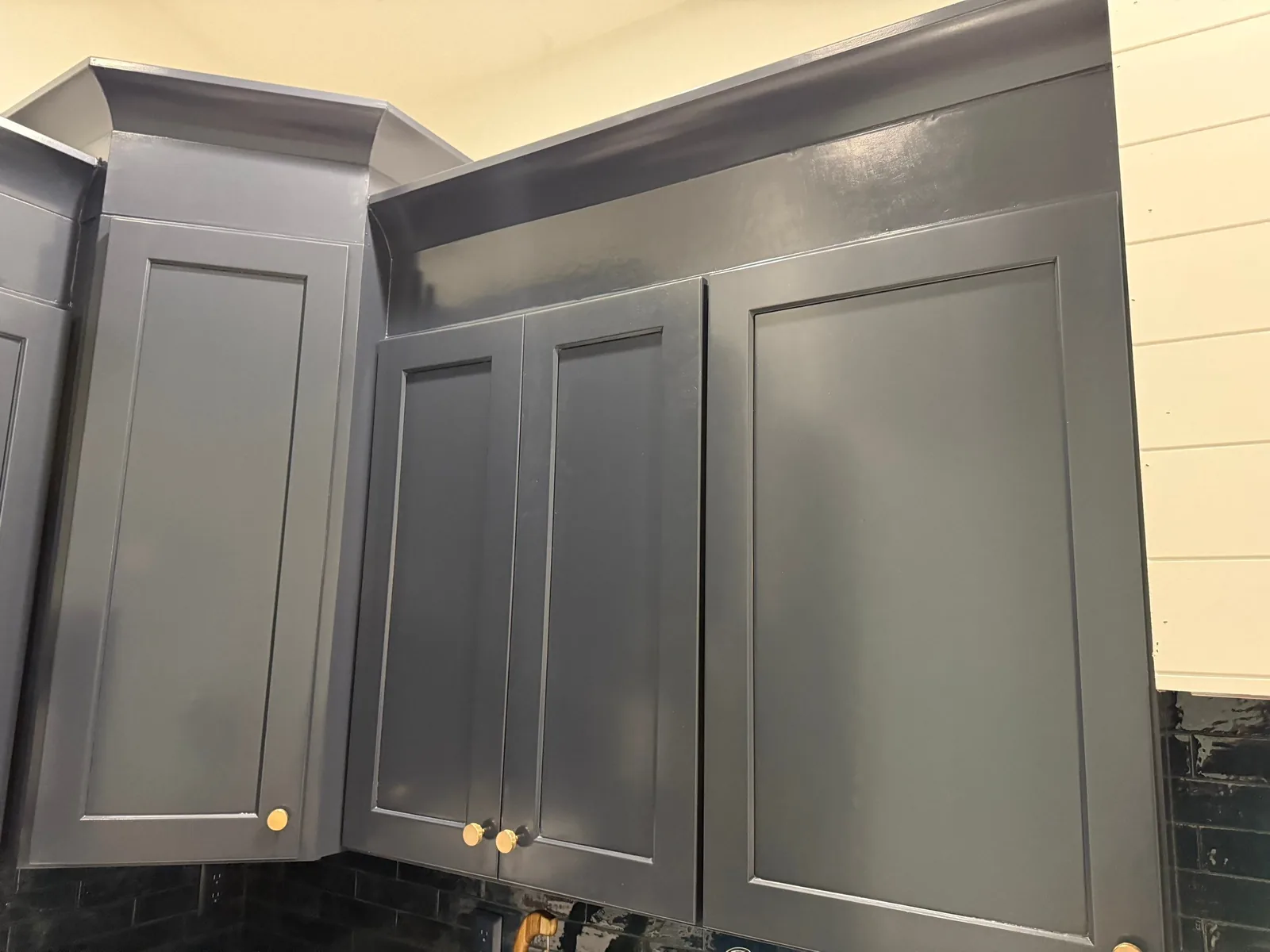 Cabinet Refinishing in Stuart, Florida. Refinished upper kitchen cabinets in dark blue-grey with shaker doors, crown moulding and brass knobs.
