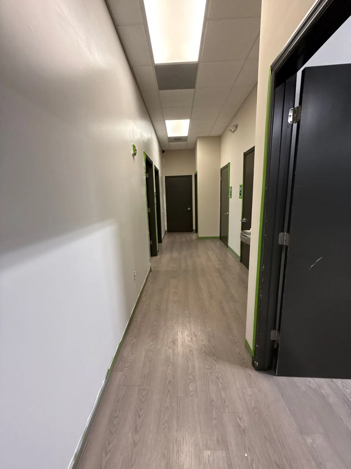 Commercial Painting in Stuart, Florida. Commercial interior corridor with cream walls, green accent trim and dark doors.