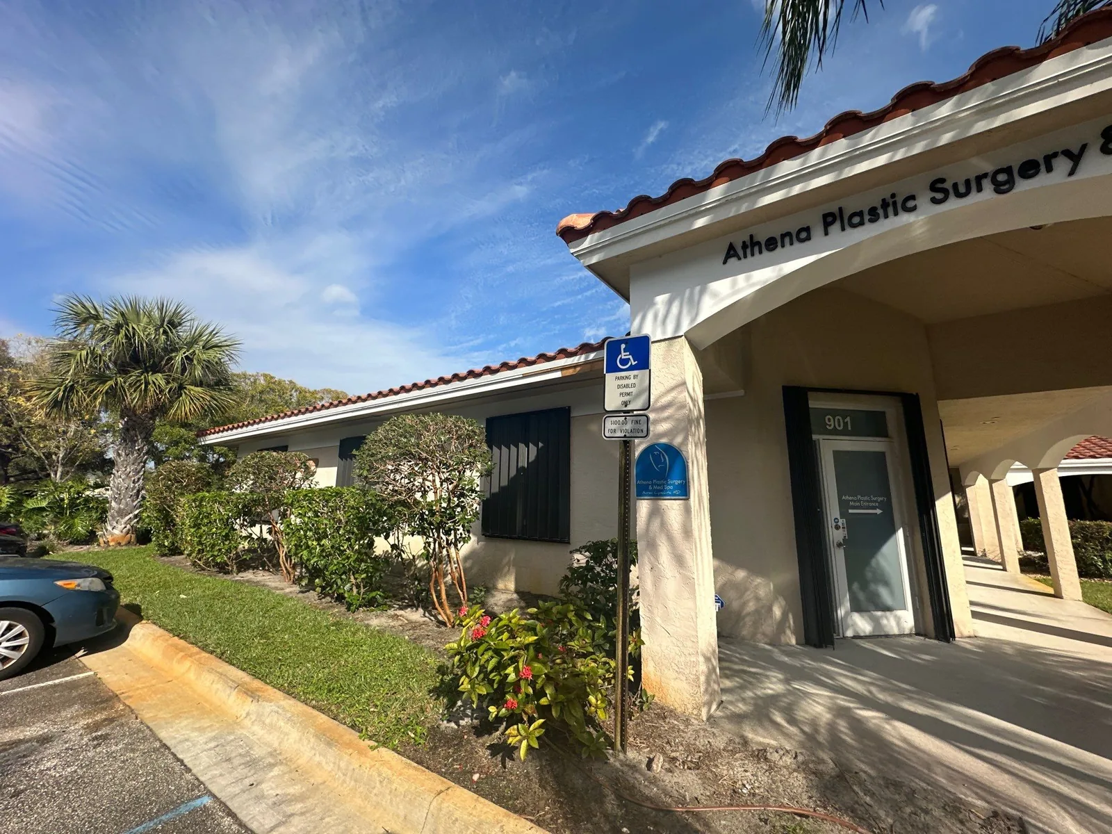 Commercial Painting in Stuart, Florida. Single-storey commercial building with cream stucco walls, tile roof and dark shutters, wall signage above the entrance.