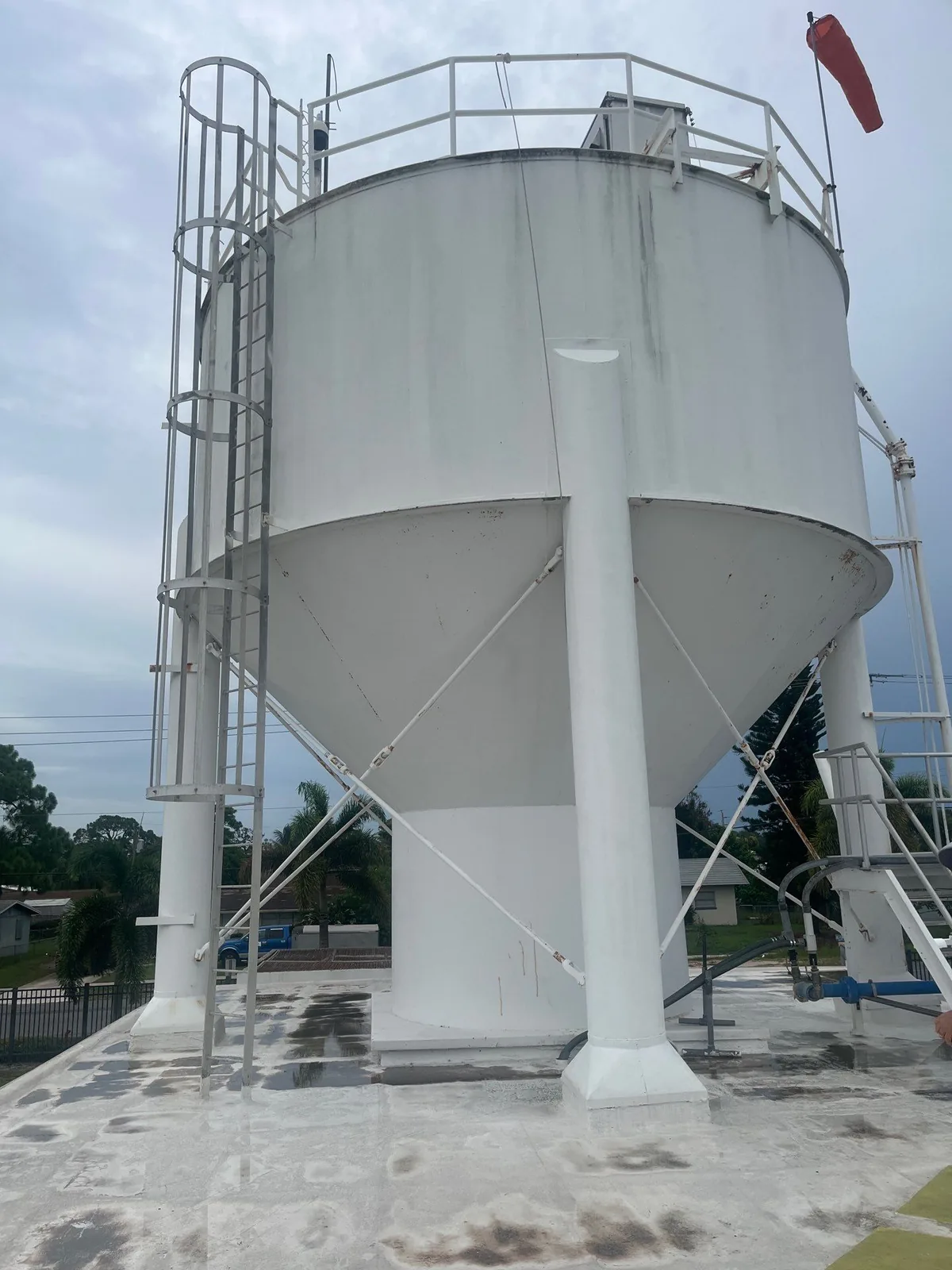 Commercial Painting in Stuart, Florida. Large white elevated industrial storage tank on legs with access ladder, freshly coated white.