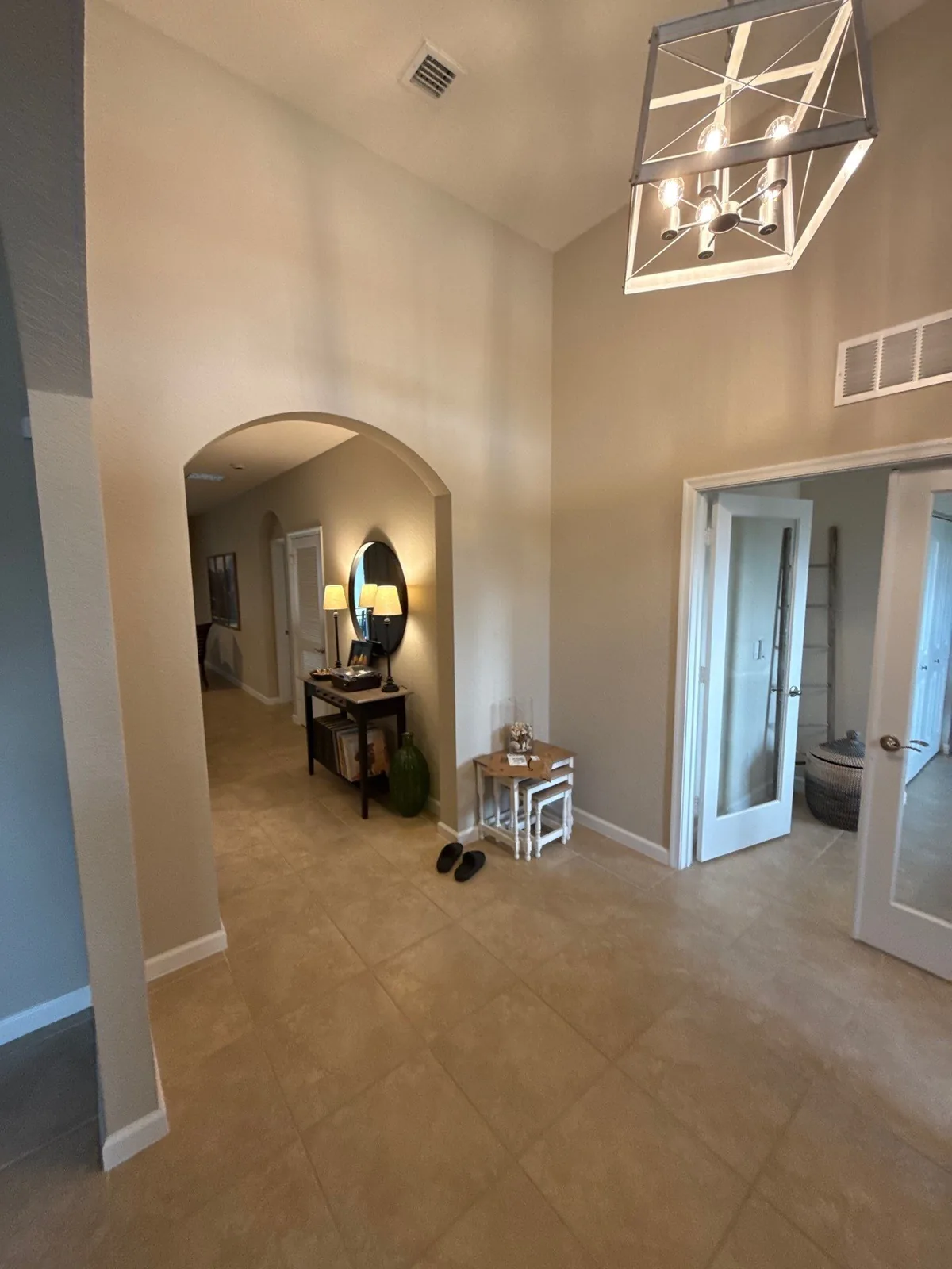 Interior Painting in Stuart, Florida. Two-storey entry foyer with arched opening, beige painted walls, white trim and lantern light fixture.
