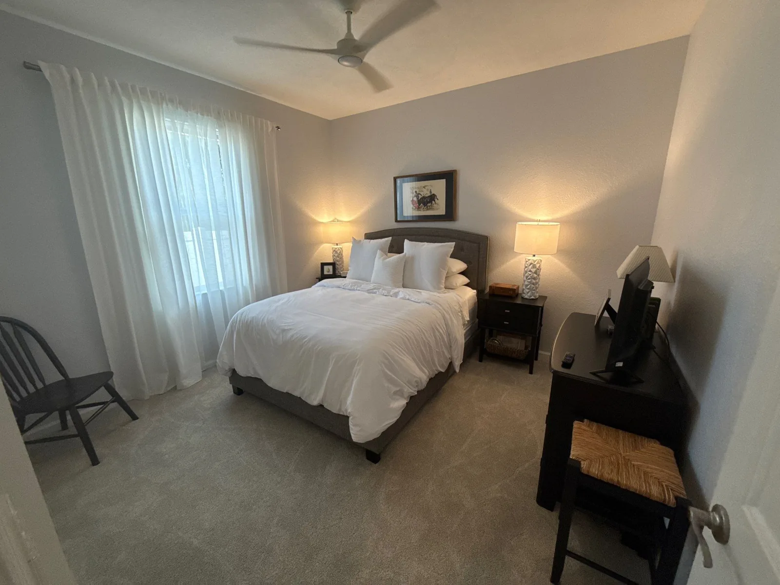Interior Painting in Stuart, Florida. Guest bedroom with light grey painted walls, white trim, made bed and two bedside lamps.
