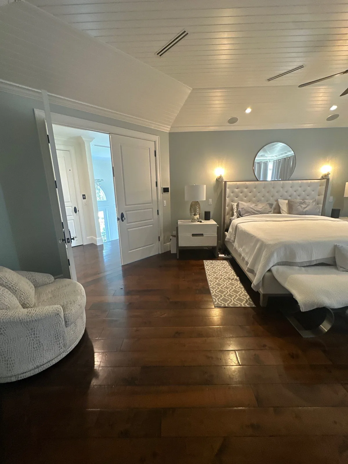 Interior Painting in Vero Beach, Florida. Furnished bedroom with pale blue-grey walls, white tongue-and-groove vaulted ceiling and dark hardwood floor.
