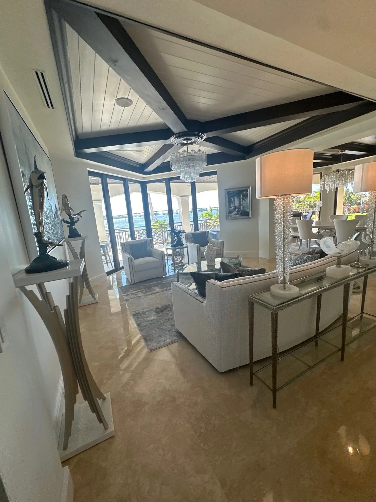 Interior Painting in Vero Beach, Florida. Furnished living room with a vaulted white plank ceiling, dark stained exposed beams and a chandelier.