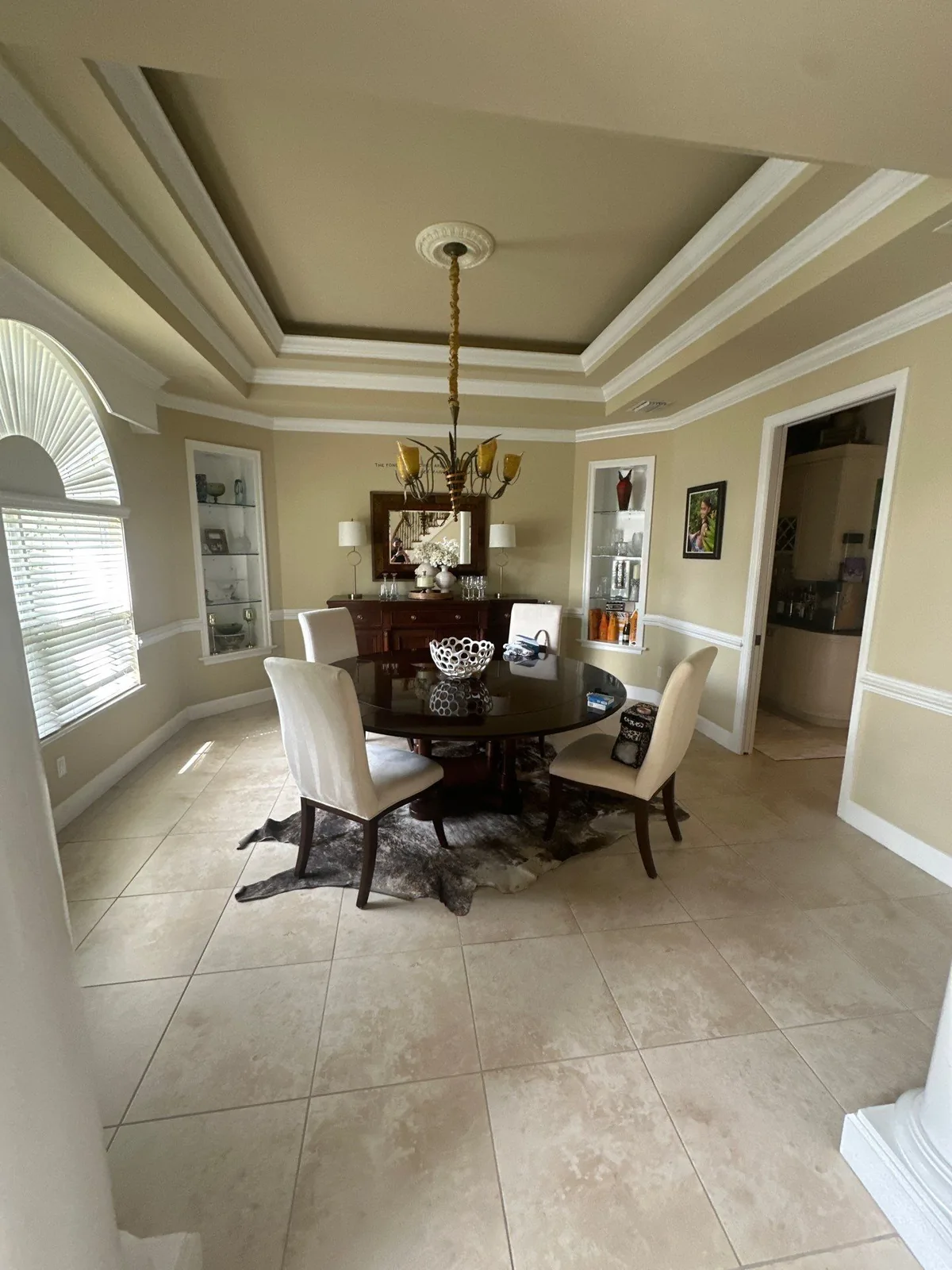 Interior Painting in Vero Beach, Florida. Dining room with stepped tray ceiling in two tones, painted walls with white crown moulding and chair rail, table and upholstered chairs in place.