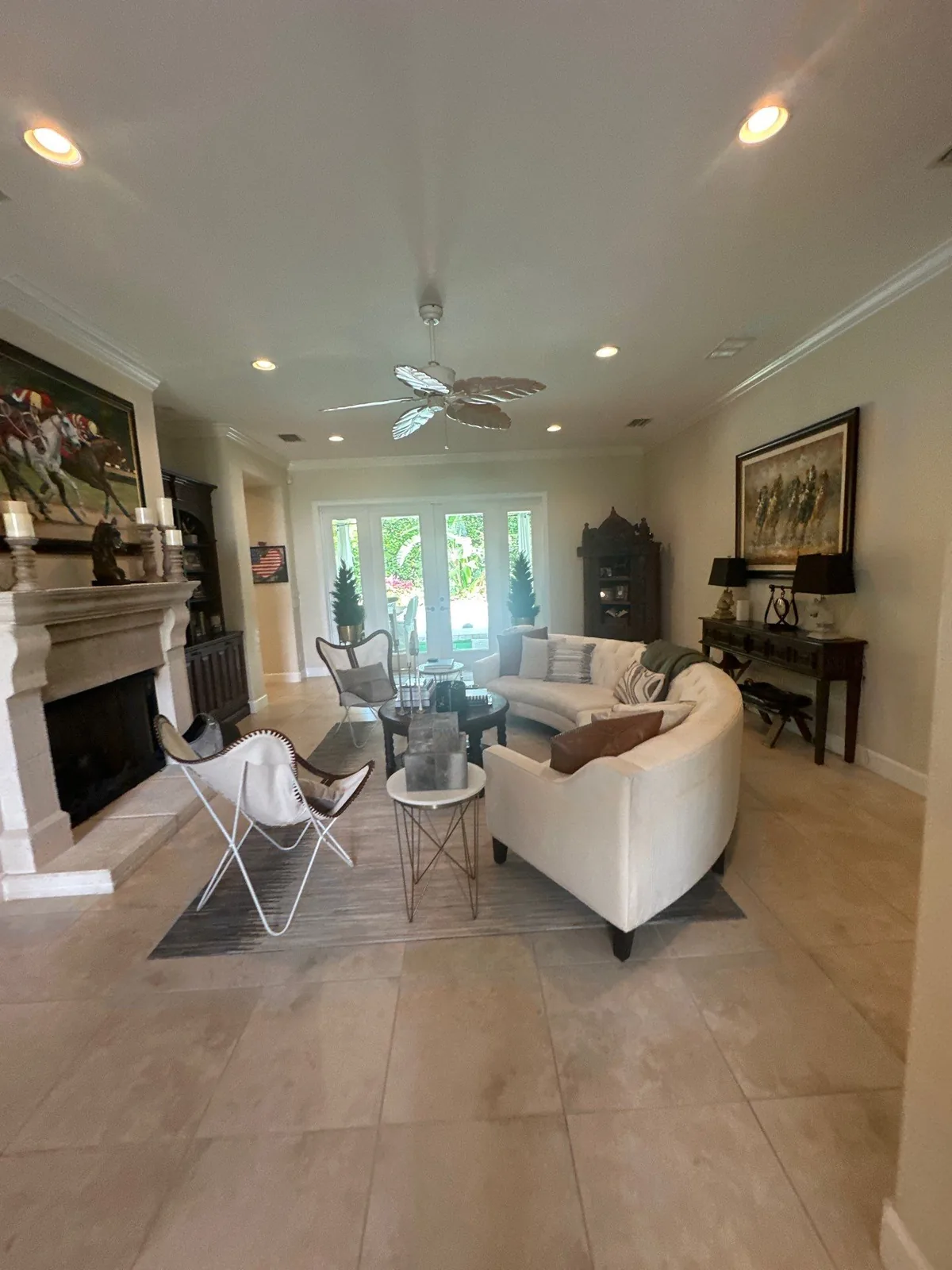Interior Painting in Vero Beach, Florida. Living room with painted walls and ceiling, white crown moulding, stone fireplace and French doors, furniture in place.