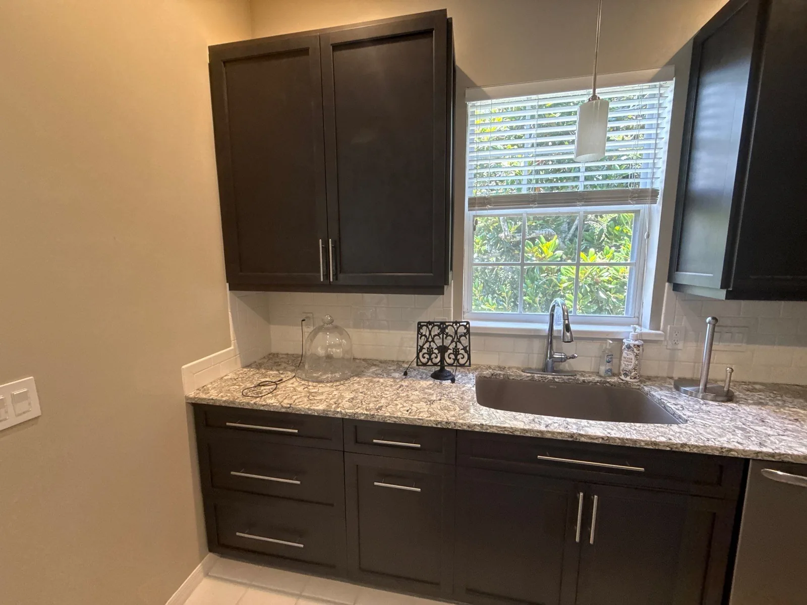 Cabinet Refinishing in Wabasso Beach, Florida. Kitchen run with dark espresso shaker cabinets, speckled granite countertop, undermount sink and a window above.