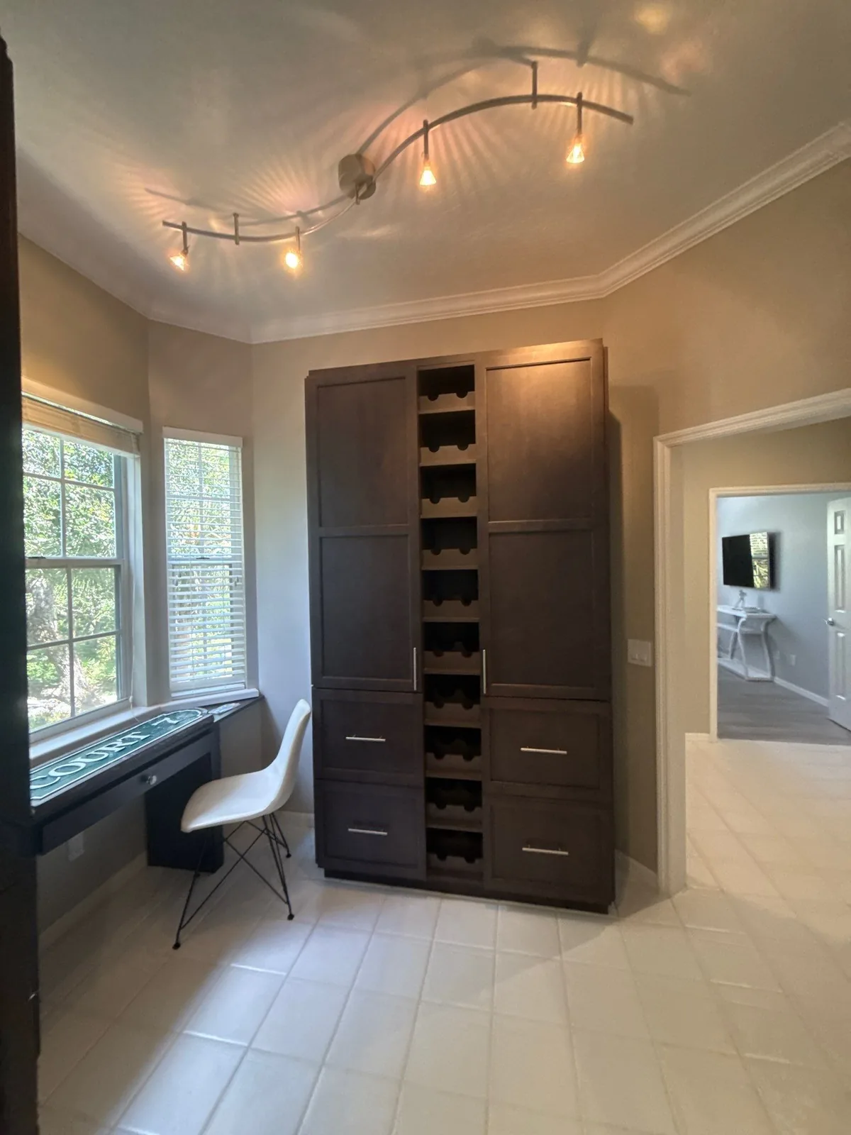 Cabinet Refinishing in Wabasso Beach, Florida. Floor-to-ceiling dark wood cabinet unit with a built-in desk nook, window seat and curved track lighting on a white ceiling.