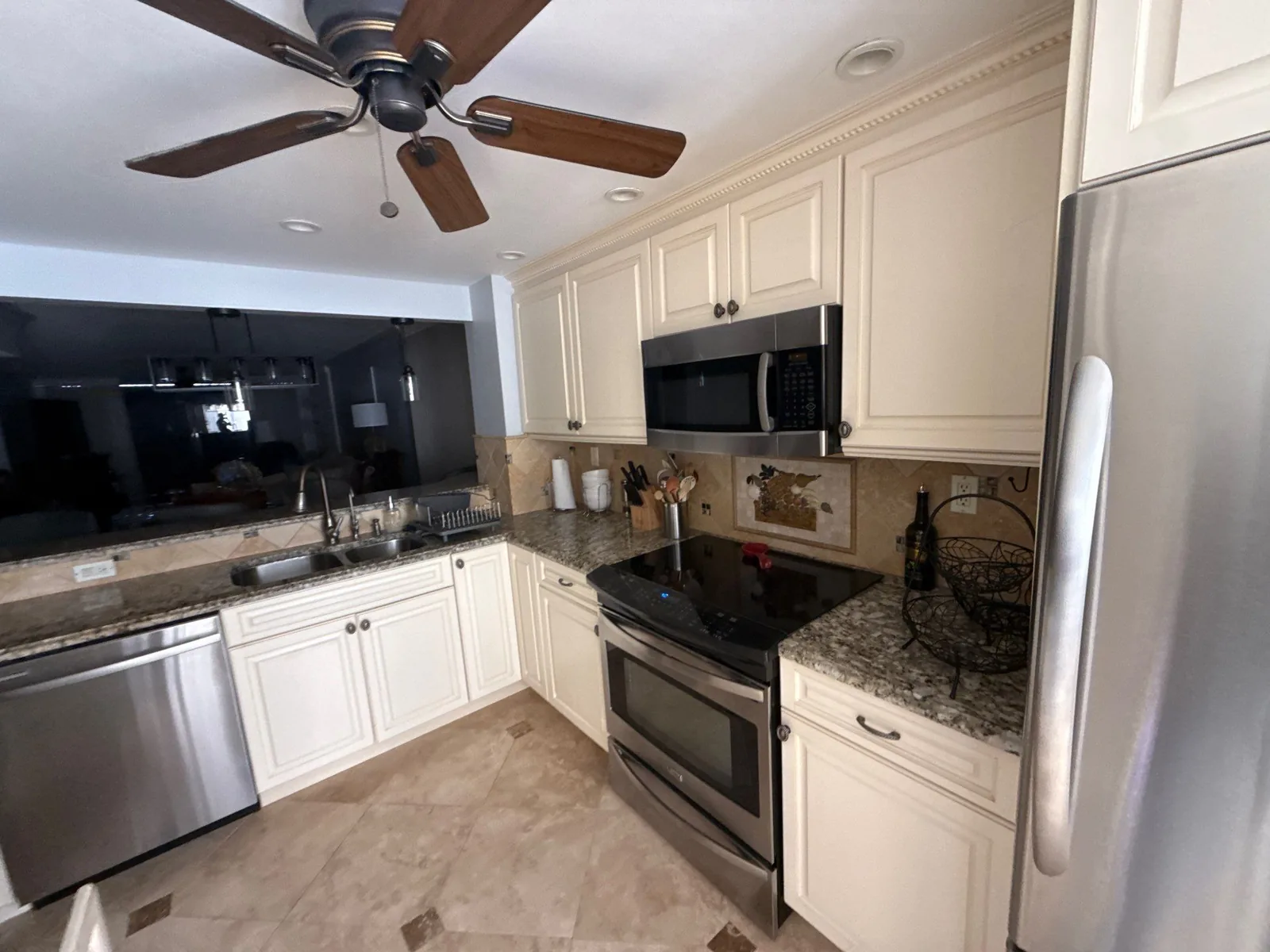 Cabinet Refinishing in Waveland, Florida. Kitchen with cream raised-panel cabinets, stone countertops, stainless range, microwave, dishwasher and refrigerator.
