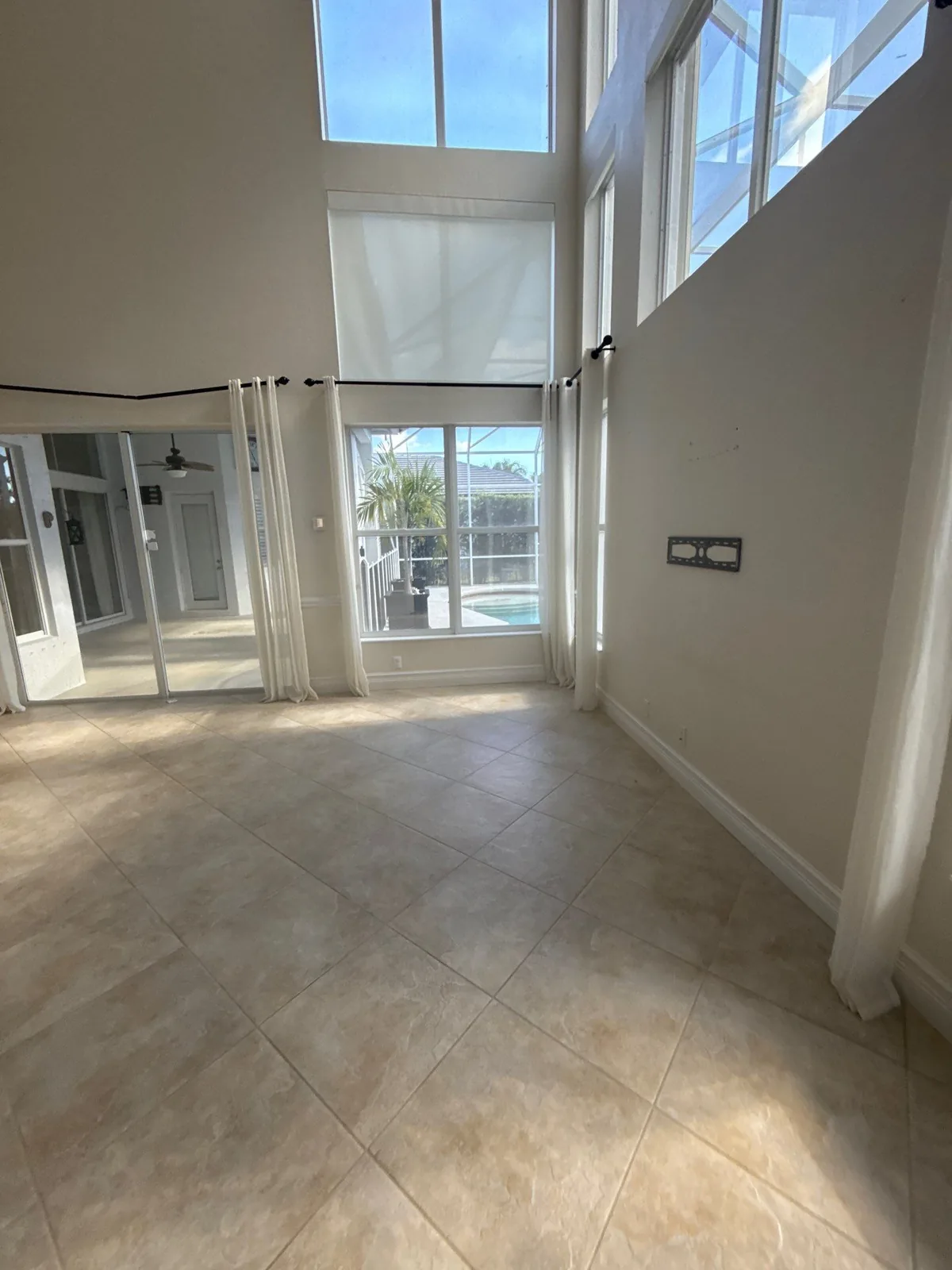 Interior Painting in Wellington, Florida. Empty two-storey living room with tall painted walls, clerestory windows and tiled floor.