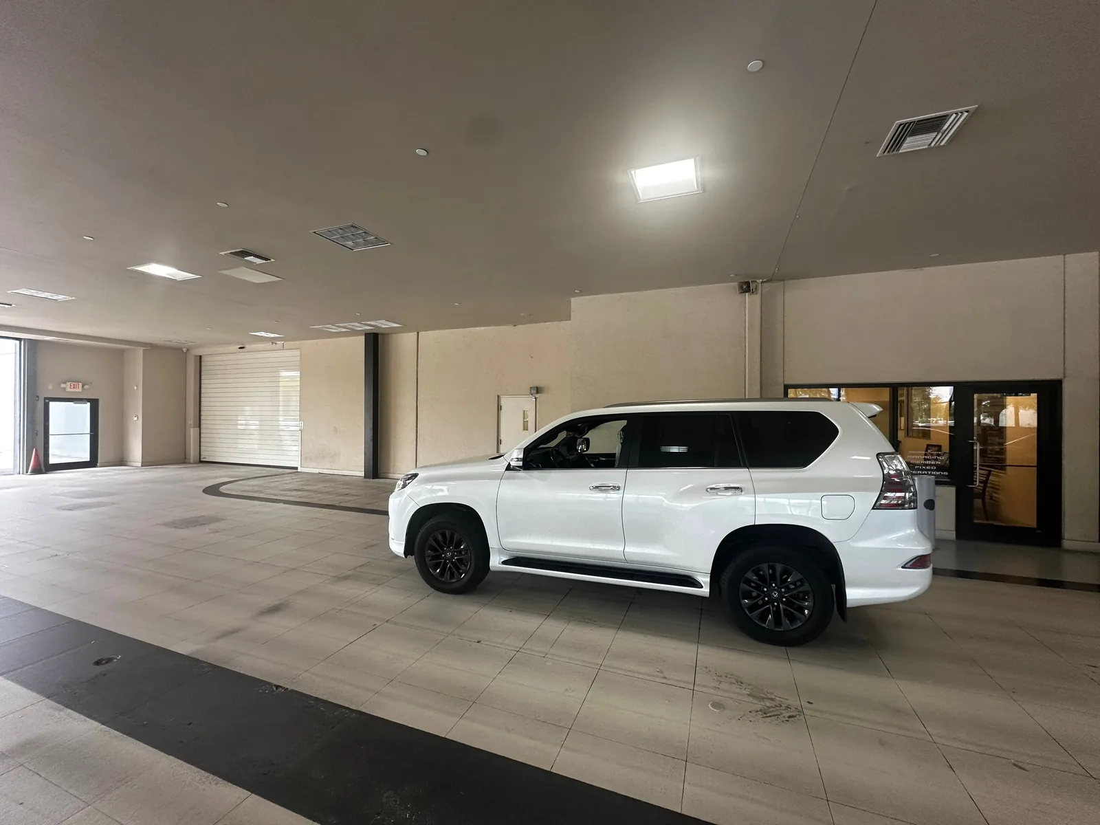 Commercial Painting in White City, Florida. Finished car dealership showroom interior, beige walls with a dark grey ceiling, white SUV on the floor.