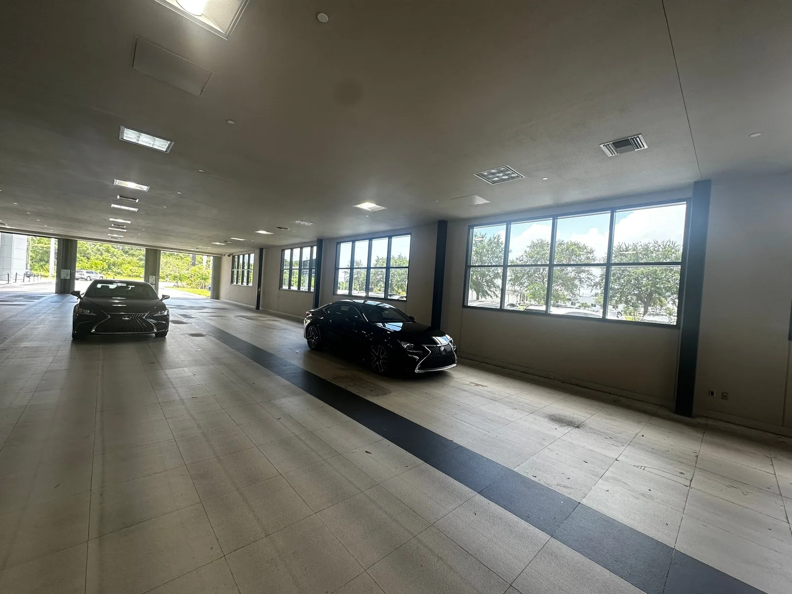 Commercial Painting in White City, Florida. Dealership showroom interior with beige walls, dark charcoal column wraps and window mullions, grey ceiling.