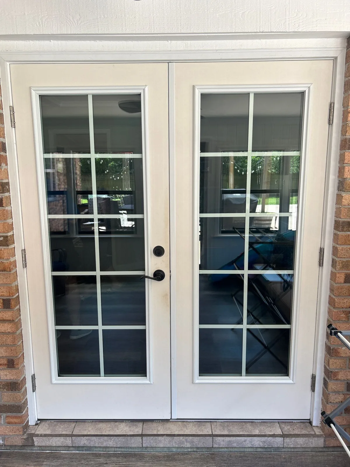 Exterior Painting in White City, Florida. Pair of white painted exterior French doors with divided-light glass set in a brick wall.