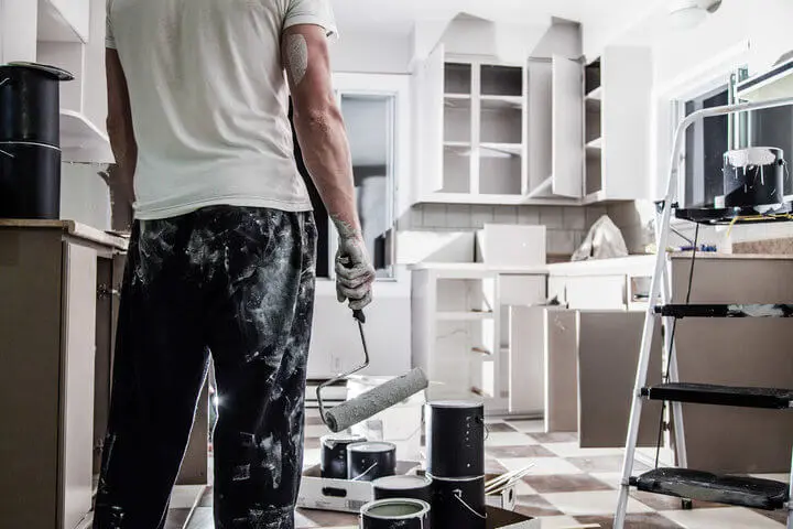 Painter refinishing kitchen cabinets in a Fort Lauderdale home